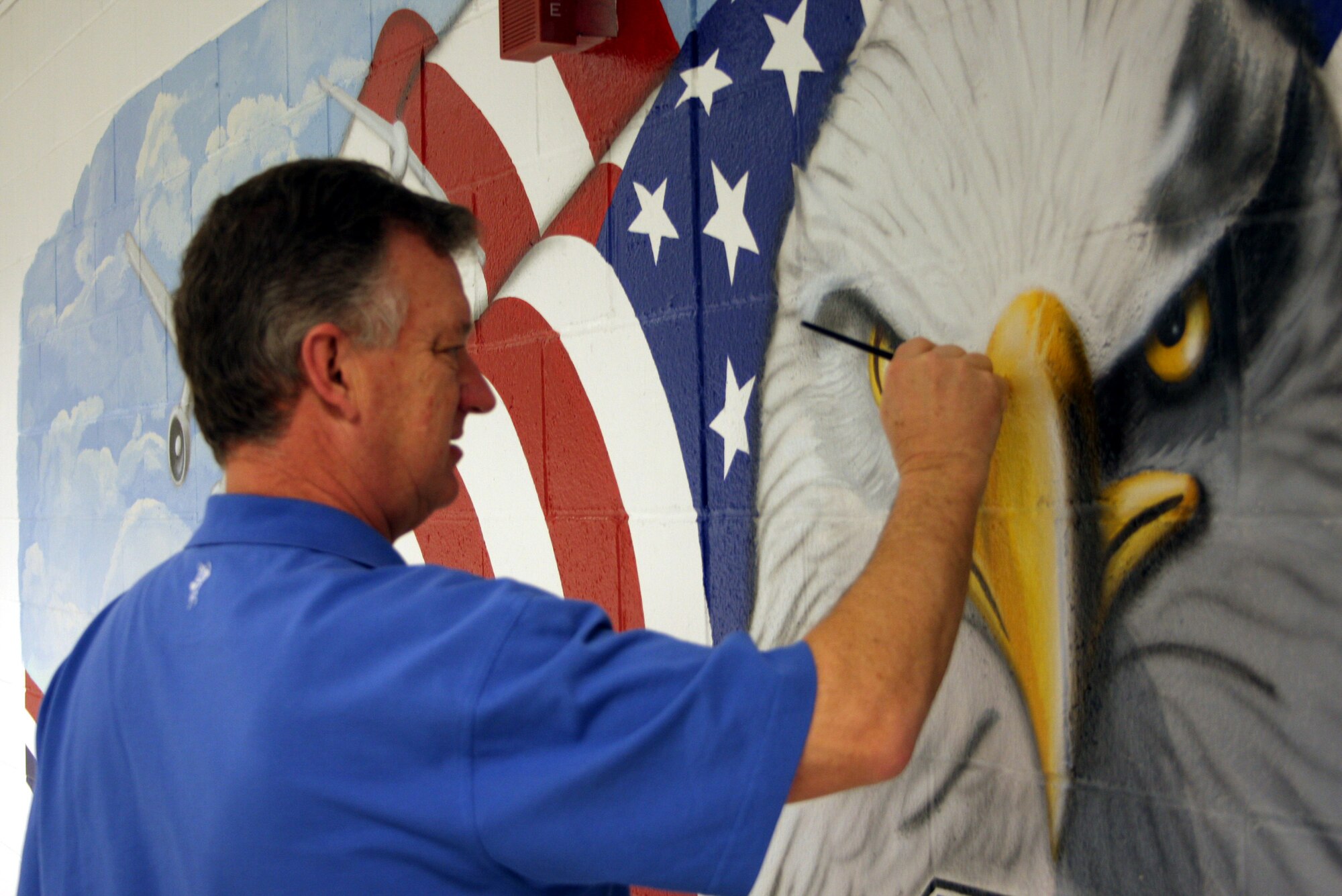 WRIGHT-PATTERSON AFB, Ohio - Master Sgt. Roland Stinnette, 445th Maintenance Operations Flight,  puts the final touches on a mural he painted in the 445th Maintenance Group building.  Sergeant Stinnette was asked by Col. Anna Schulte, 445th Maintenance Group commander, to design the mural.  The mural represents a collage of the 445th since its inception at Wright-Patterson Air Force Base in 1994.  In addition to being a reservist, Sergeant Stinnette is an illustrator for the 88th Air Base Wing Services division. (Air Force photo/Maj. Cynthia Harris)