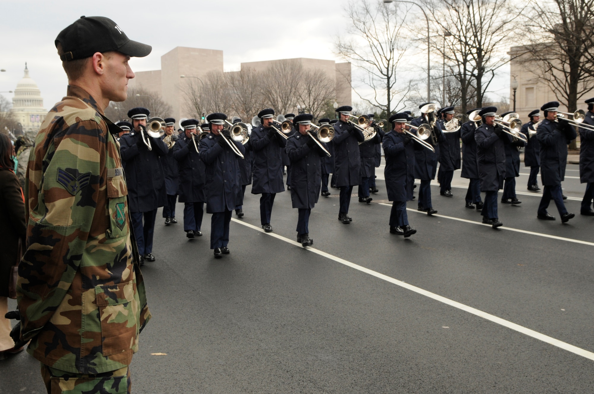 Senior Airman Gregory A. Benhase, 844th Communications Group, stands at parade rest as the United States Air Force Band’s Ceremonial Brass marches by Jan. 11 in Washington during a practice run of the inauguration parade for President-elect Barack Obama. (U.S. Air Force photo by Senior Airman Tim Chacon)