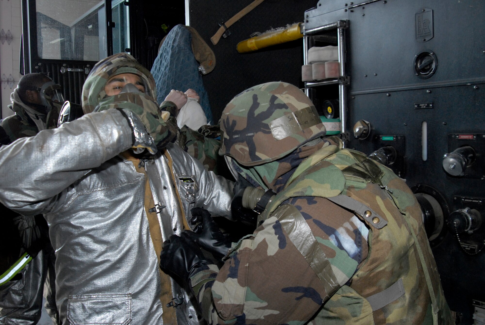 Members of the 8th Civil Engineer Squadron Fire Department help each other put fire retardant suits over their Mission Oriented Protective Posture gear during the Peninsula Wide Operation Readiness Exercise at Kunsan Air Base, Republic of Korea, Jan. 13, 2009. Even in MOPP gear, Kunsan's Fire Fighters have seven minutes from the time they are dispatched to respond to an incident. (U.S. Air Force Photo by SSgt Jason Colbert)