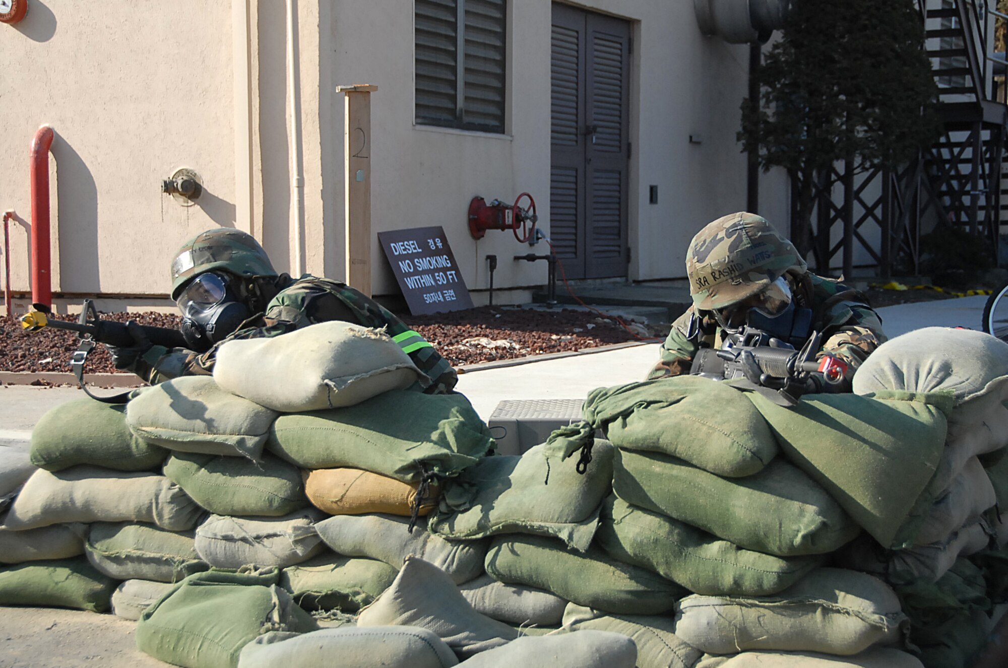 Senior Airman Rashid Watts (right), and Airman Stacy Coffman provide security for post attack reconnaissance teams after a simulated ground burst attack during Exercise Beverly Bulldog 09-01 Jan. 13. PAR teams are released from sheltering in place to conduct assessments of facilities to look for damage, signs of contamination and unexploded ordnance. Both Airman Watts and Coffman are assigned to the 51st Mission Support Squadron. (U.S. Air Force photo/Master Sgt. Paul Kilgallon)
