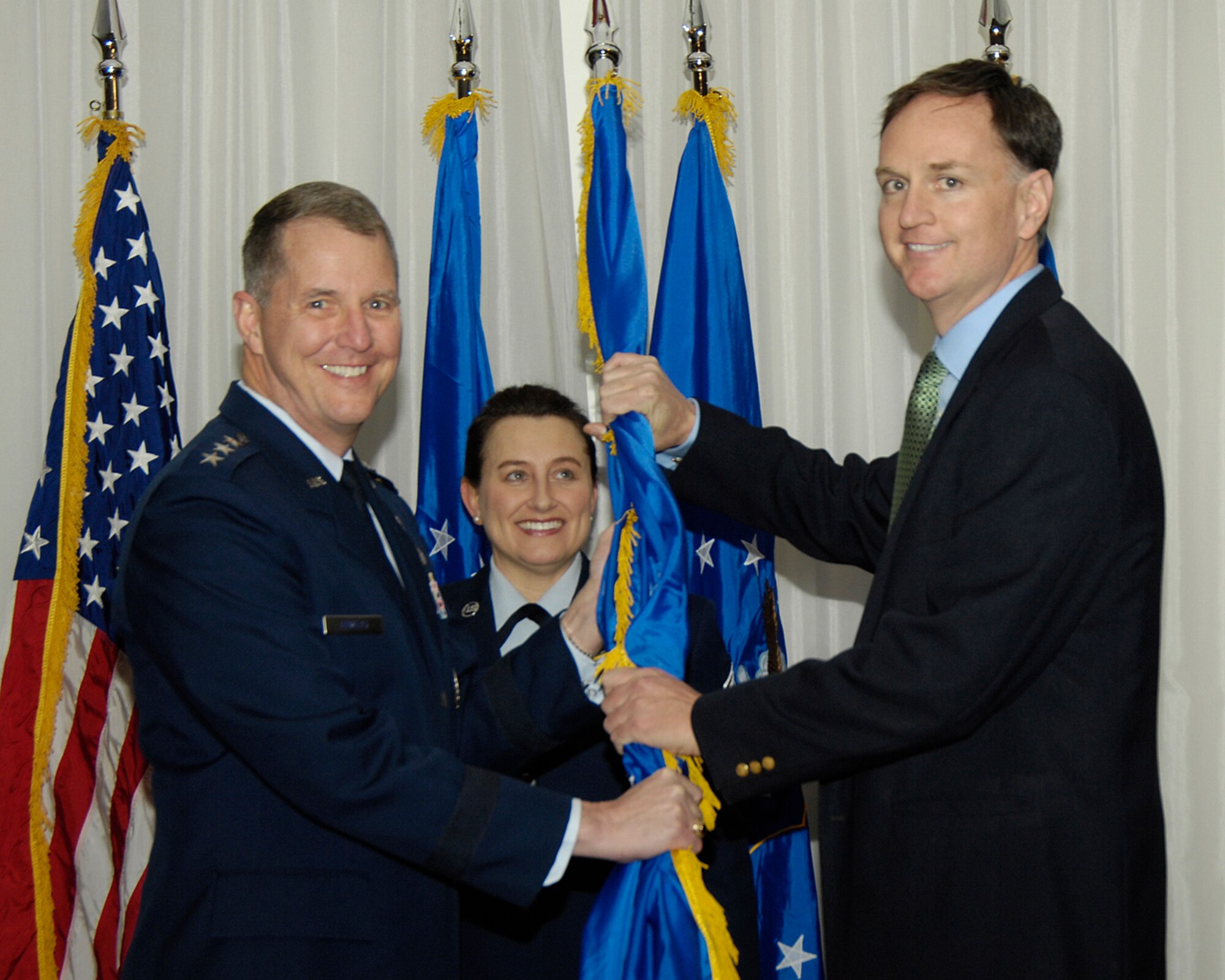 HANSCOM AIR FORCE BASE, Mass. - Lt. Gen. Ted Bowlds, Electronic Systems Center commander (left), passes the guidon flag to Michael Graham, host of the daily radio talk show, The Natural Truth, on WTKK in Boston, marking his induction into Hanscom's Honorary Commander program, while Chief Master Sgt. Karen McCoy, ESC command chief looks on. (U.S. Air Force photo by Linda LaBonte Britt)