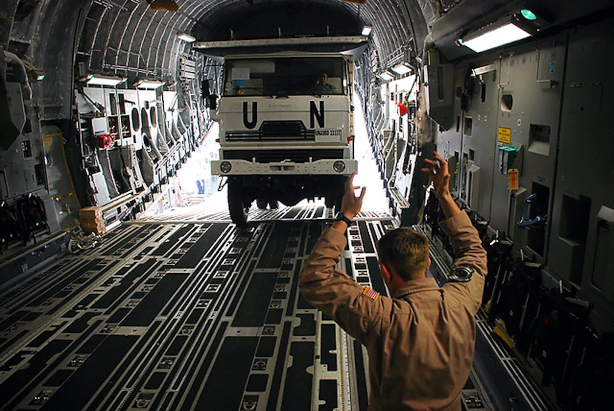 Technical Sgt. Sean Arnold guides Rwandan defense force trucks on board a C-17 Globemaster III Jan. 13 at Kigali International Airport in Rwanda. This is the first load of five airlifts to the United Nations-African Union mission in Darfur. Sergeant Arnold is from Travis Air Force Base, Calif. (U.S. Air Force photo/Staff Sgt. Samuel Bendet) 
