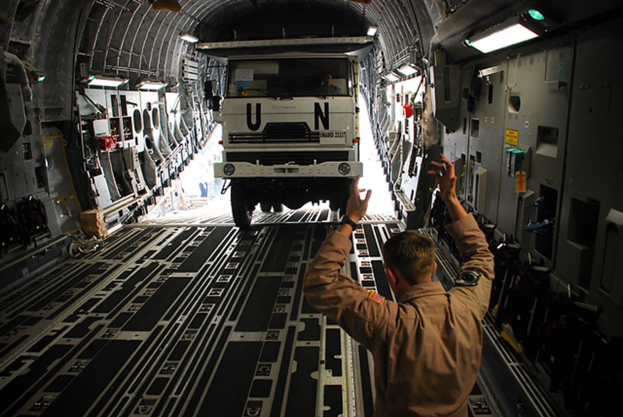Kigali International Airport, Rwanda--Tech. Sgt. Sean Arnold, Travis AFB, Calif.,  guides Rwandan Defense Force trucks on board a C-17 Globemaster III. This is the first load of five airlifts to the United Nations-African Union mission in Darfur. (Photo by Staff Sgt. Samuel Bendet, US Africa Command)