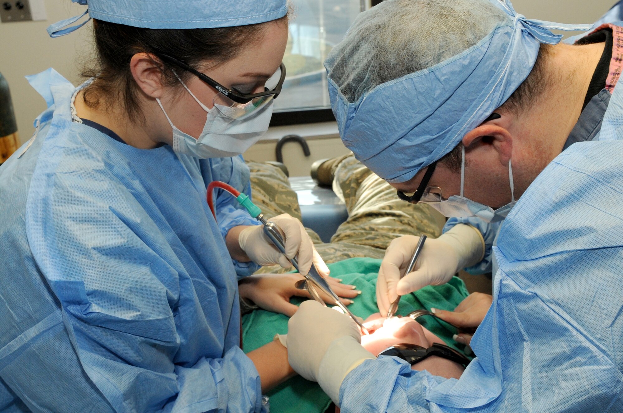 Maj. Michelle Moffa and Capt. Shawn McMahon, both 305th Dental Squadron dentists, perform oral surgery Jan. 9 at the Dental Clinic. The surgery is a tooth extraction on Airman 1st Class Daniela Watkins, 305th Aerial Port Squadron. (U.S. Air Force photo/Wayne Russell)