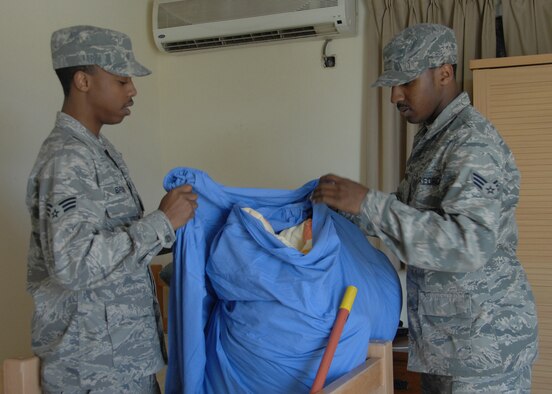 SOUTHWEST ASIA -- Senior Airman Reginald Brown and Senior Airman Maurice Monroe, 386th Expeditionary Force Support Squadron, collect used sheets during their daily duties as the lodging Tiger Team, Jan. 10, at an air base in Southwest Asia. The Tiger Team has the responsibility of cleaning the tents, making sure the grounds are clean and the trash is disposed of properly. (U.S. Air Force photo/Senior Airman Courtney Richardson)