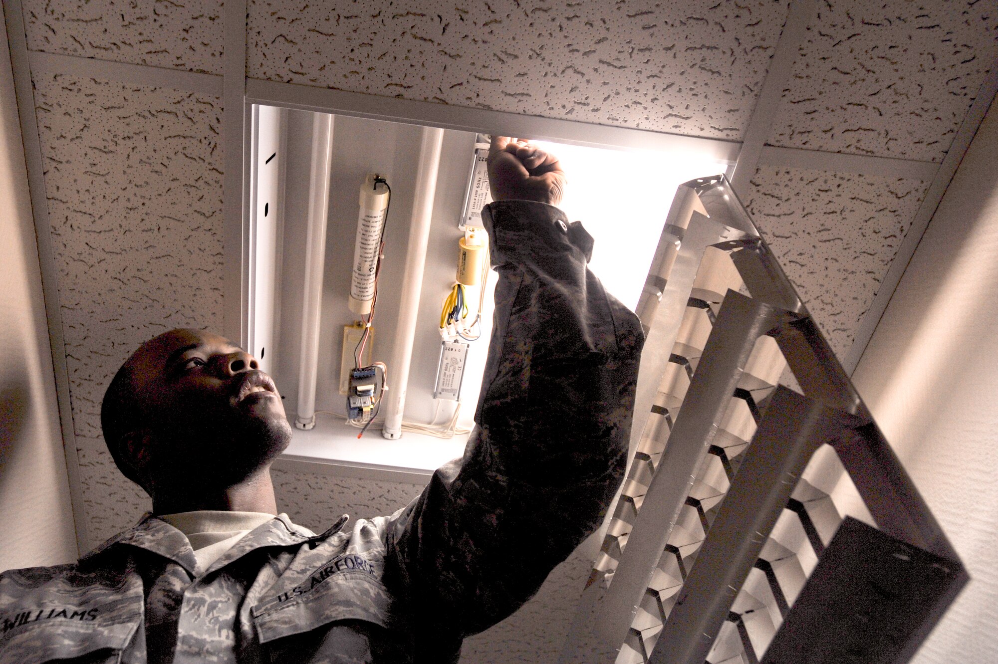 Senior Airman Augustus Williams, a 379th Expeditionary Civil Engineer Squadron Electrician, checks the starters in a light fixture, Jan. 14, 2009, in an undisclosed location in Southwest Asia.  Airman Williams and fellow members of the Electric Shop handle a majority of the electrical maintenance on base. Airman Williams is native to Augusta Ga., and is deployed from Pope Air Force Base, N.C. in support of Operations Iraqi and Enduring Freedom and Joint Task Force-Horn of Africa.(U.S. Air Force Photo by Staff Sgt. Joshua Garcia/Released)