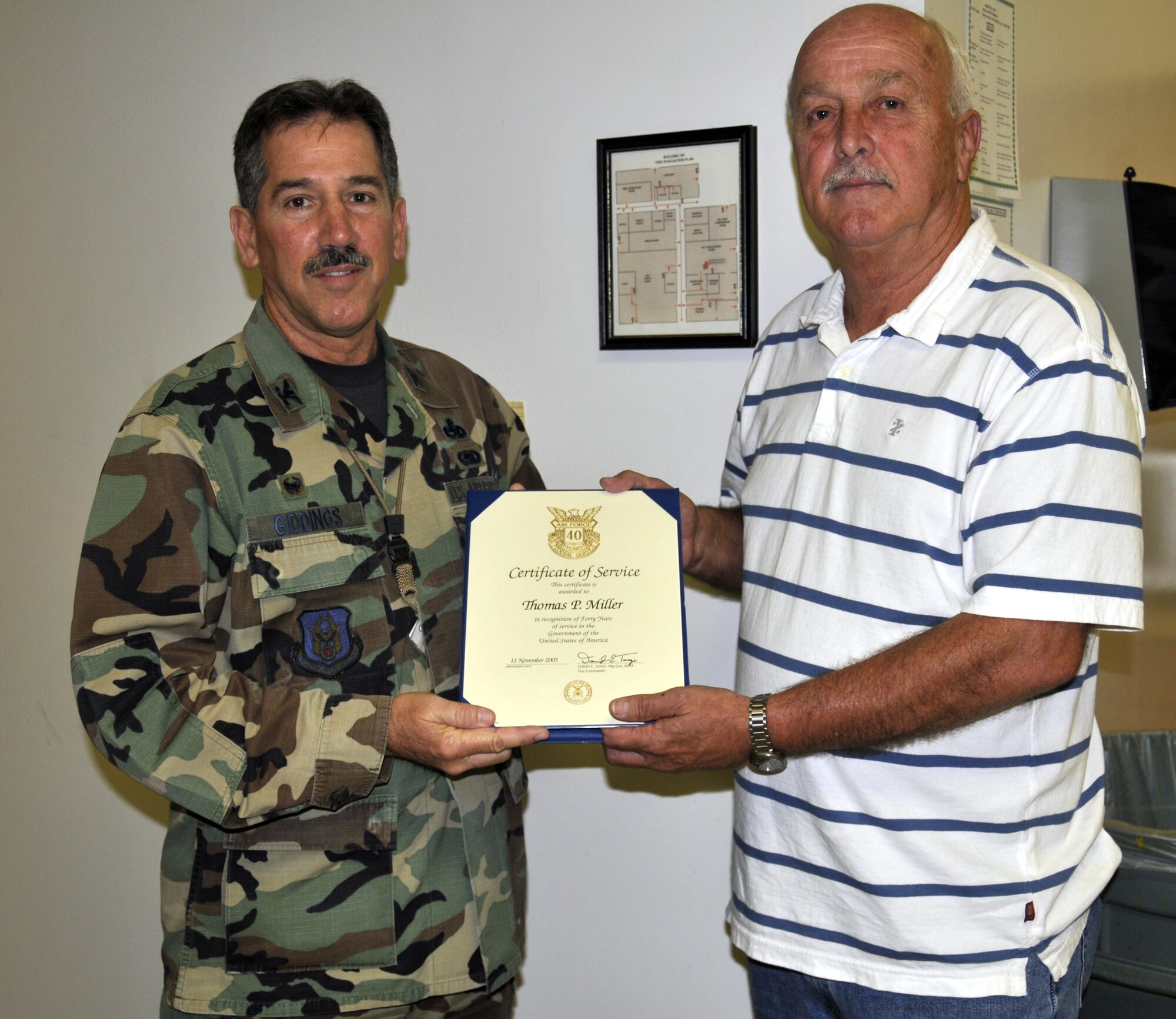 During a brief ceremony in recognition of 40 years of service to the U.S. government, Colonel Melvin Giddings, 482nd Maintenance Group commander, presents Mr. Thomas Miller, 482nd Maintenance Squadron, a Certificate of Service on Jan. 15.  Mr. Miller entered the Air Force on active duty in 1963 as an instruments and auto pilot specialist stationed at Dyess Air Force Base, Texas.  After tours of duty in Vietnam and Taiwan, Miller came to Homestead AFB in 1974 as an Air Force Reservist working on C-121 transport aircraft.  In later years, he worked on instrumentation and avionic systems of F-4 and F-16 fighter jets.  Mr. Miller currently works in the 482nd Avionics Flight coordinating calibration and repair of all precession measurement and test equipment. (U.S. Air Force photo/Tim Norton)