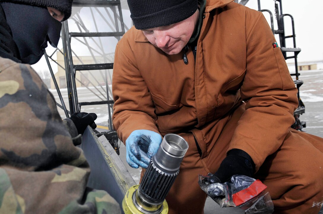 (Left to Right) Tech Sgt. Chad Hopson and Staff Sgt. Joseph Canet, 28th Aerospace Maintenance Squadron dedicated crew chiefs, apply anti-seize compound onto a structural mode control vane here, Jan. 15. The anti-seize compound helps prevent the structural mode control vane from sliding when reinstalled to the B-1B Lancer.(US Air Force photo/Airman 1st Class Corey Hook)