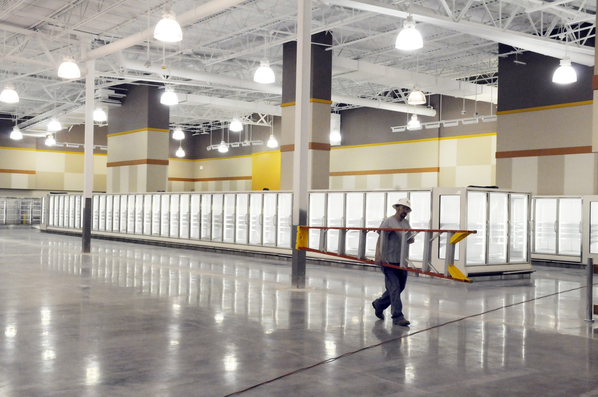A workier carries a ladder inside the new commissary at Robins that is scheduled to open April 23. U. S. Air Force photo by Sue Sapp