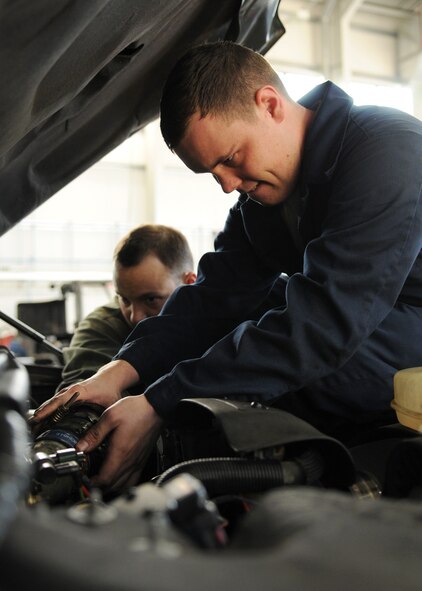 Airman 1st Class Timothy Reuwer, in blue coveralls, and Staff Sgt. Justin Creel,  both 100th Logistics Readiness Squadron vehicle maintenance technicians, install a clamp after repairing a power steering pump leak Dec. 18, 2008, at RAF Mildenhall, England. The vehicle maintenance squadron performs annual inspections on more than 640 government vehicles at RAF Mildenhall, while also servicing and repairing vehicles daily. (U.S. Air Force photo by Staff Sgt. Jerry Fleshman) 
