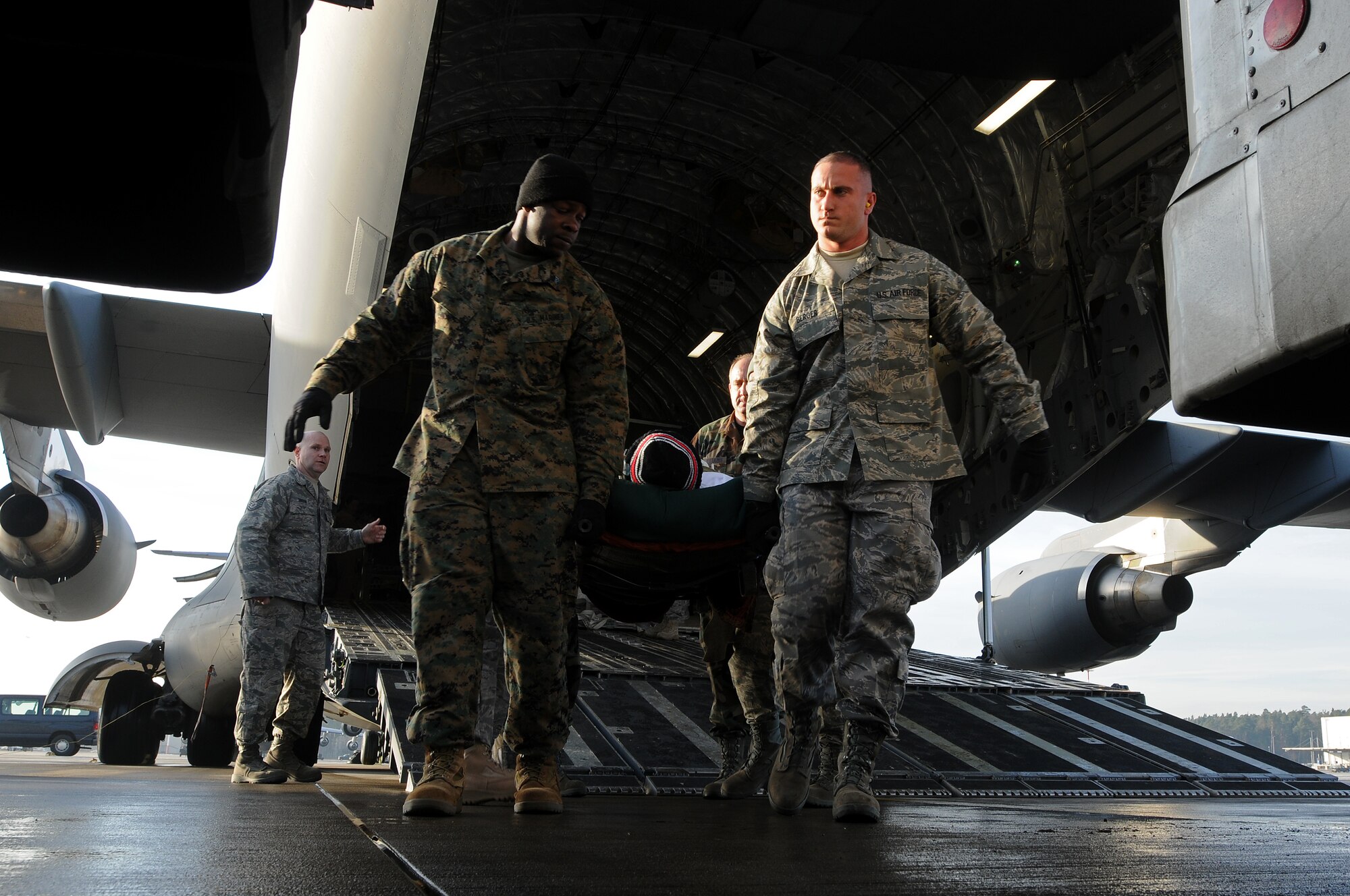 Marine Corps and Air Force personnel from the 435th Contingency Aeromedical Staging Facility work together at Ramstein Air Base to off-load patients returning from Balad Air Base, Iraq, Jan. 13, 2009. More than 30 patients who were wounded in battle were flown back from the Area of Operation. (U.S. Air Force photo by Airman 1st Class Kenny Holston)  