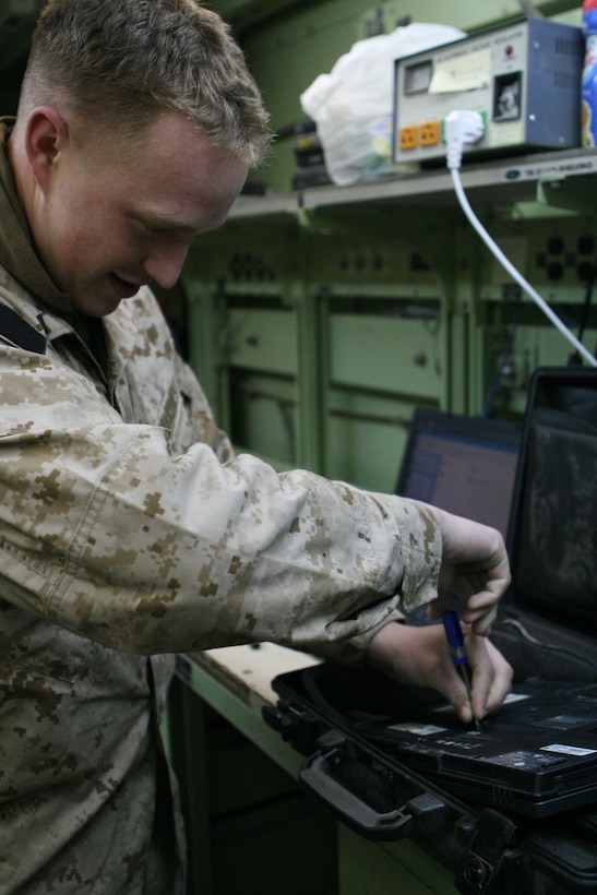 Lance Cpl. Christopher Jourden, a maintenance technician from RCT-8 communications section, removes a hard drive from a broken laptop.  Jourden says as a technician he does a substantial amount of work on computers.  Properly working computers are a key factor in ensuring that Marines are able to transfer and receive information.