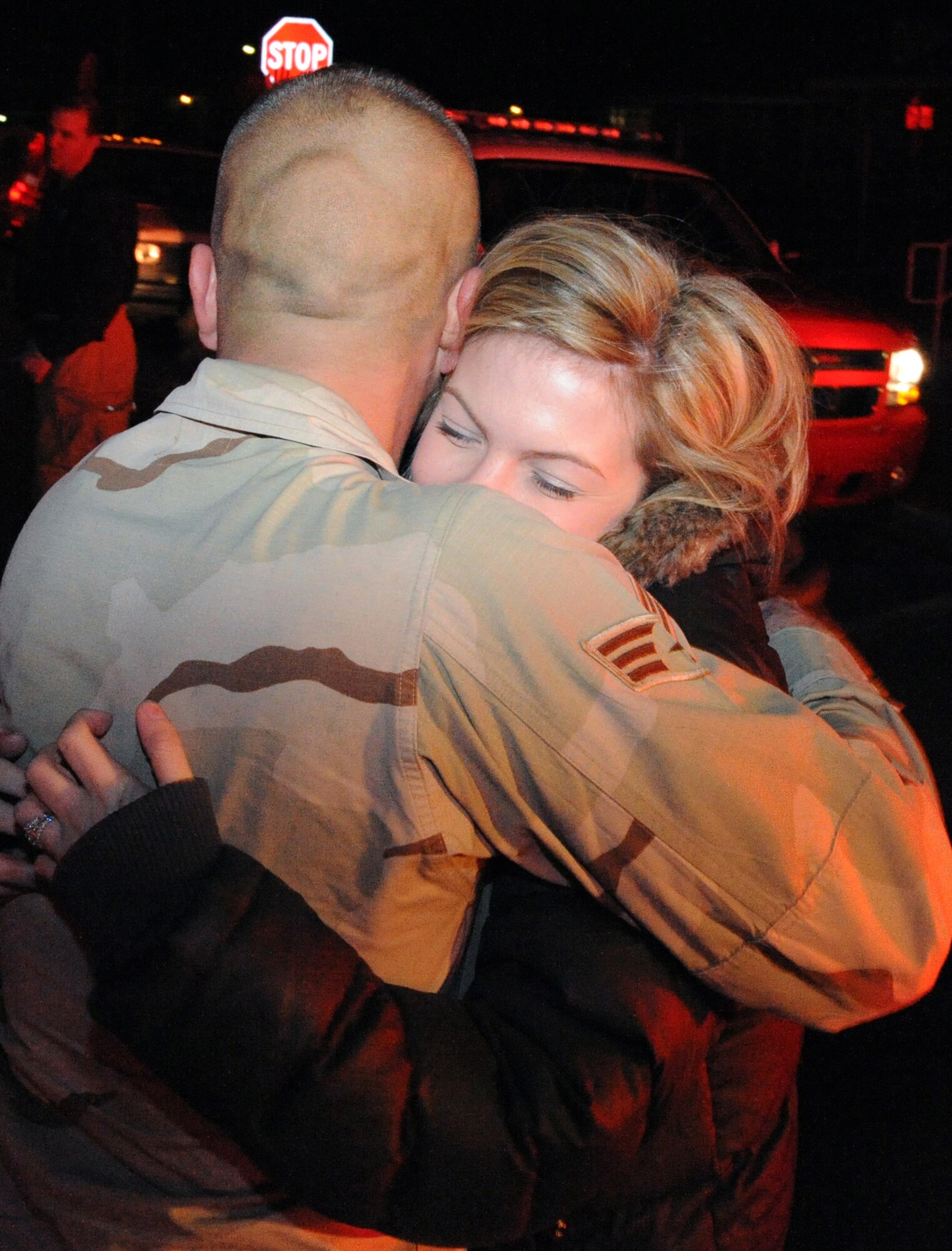 Senior Airman Derek Larson, 436th Civil Engineer Squadron and City of Dover volunteer firefighter, hugs his wife, Lindsay, upon arriving to his home in Dover Jan. 16. Airman Larson returned from a deployment to Joint Base Balad, Iraq, and was escorted to his home by more than 20 City of Dover firefighters, local police and five fire engines. (U.S. Air Force photo/Tech. Sgt. Kevin Wallace)
