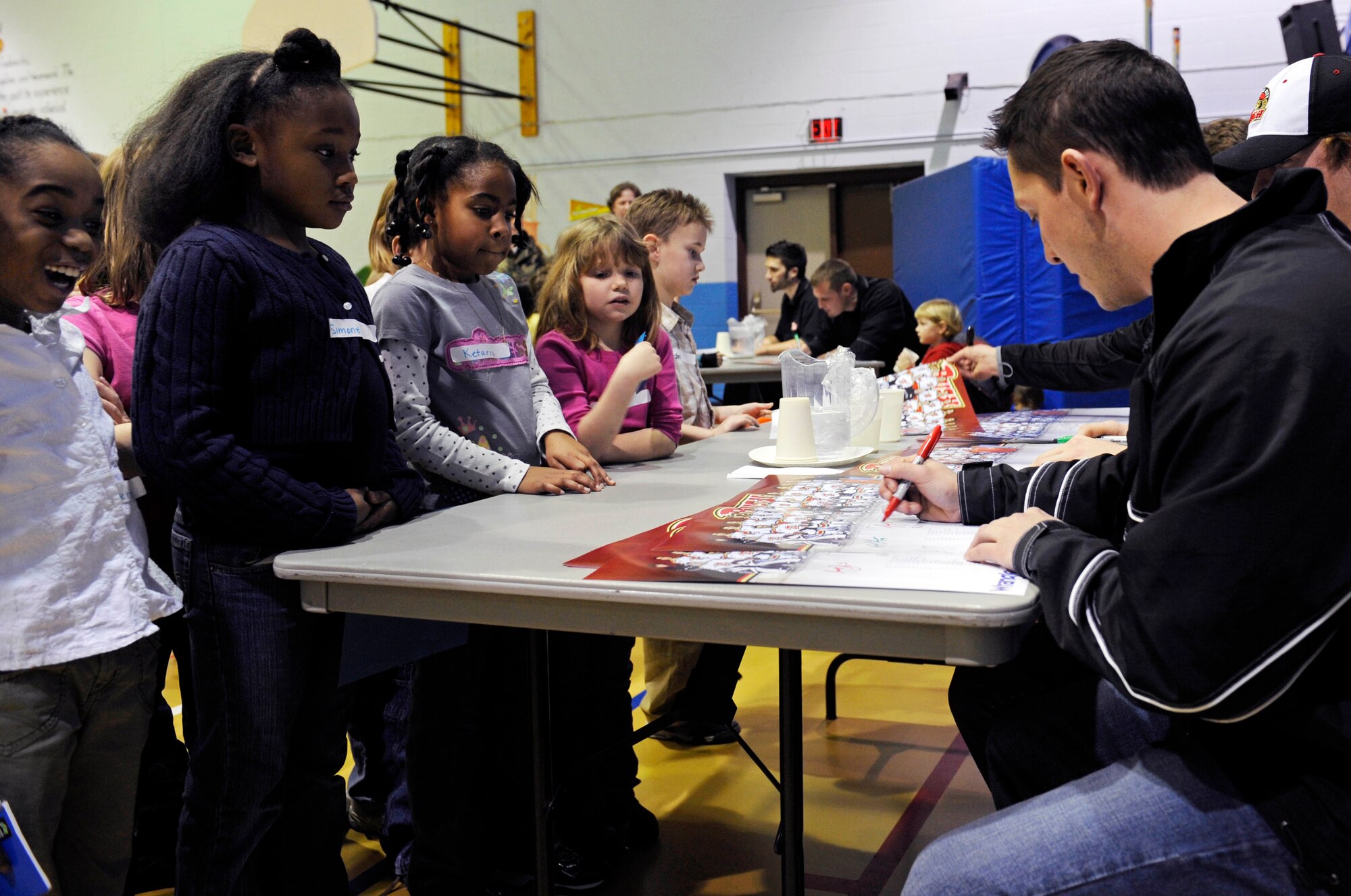 Joey Olson of the Rapid City Rush hockey team signs autographs for the children at the Ellsworth Youth Center here, Jan. 15. Members of the team signed posters, sticks, and pucks for the kids. (US Air Force photo/Airman 1st Class Corey Hook)