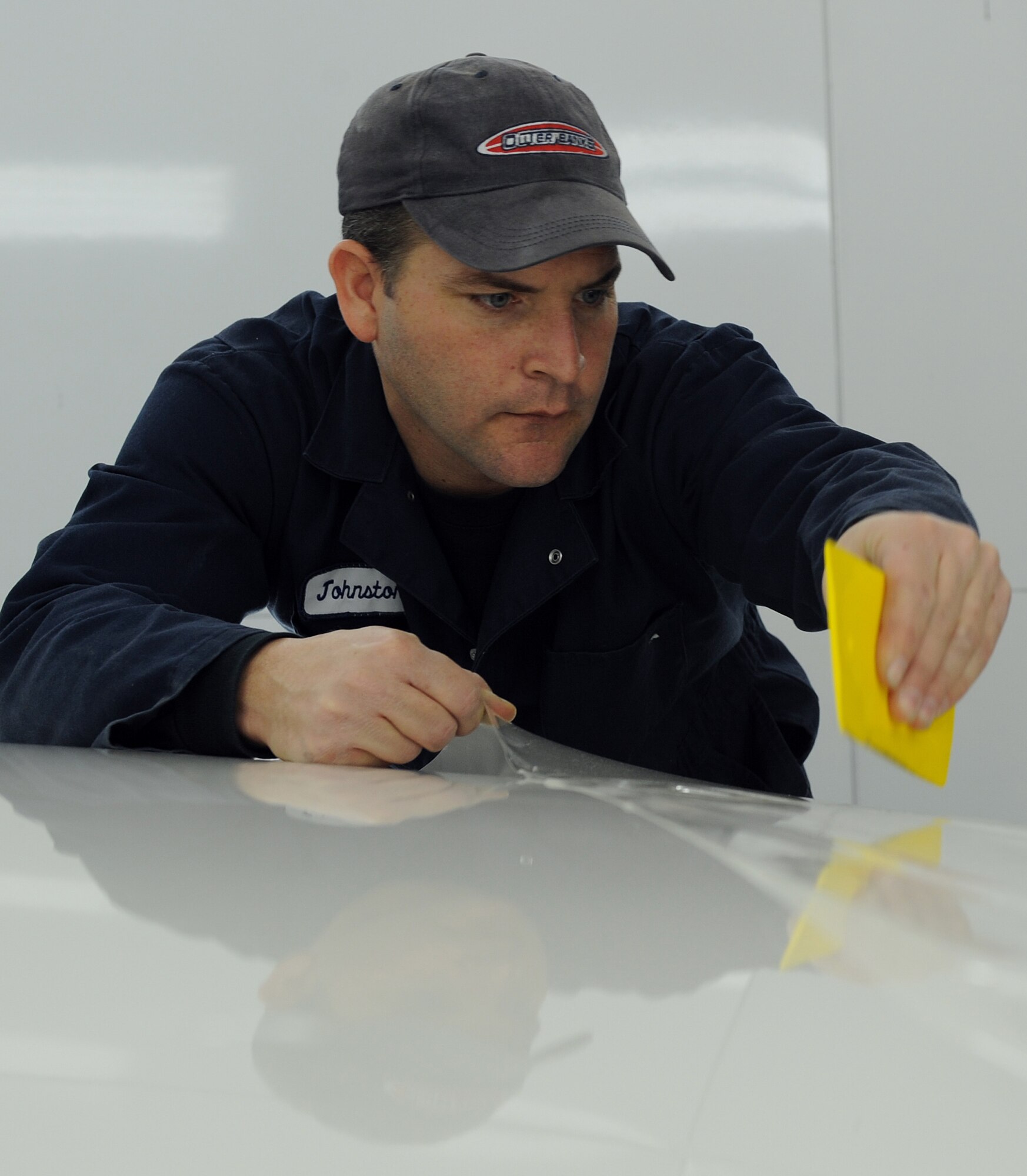 LANGLEY AIR FORCE BASE, Va. -- Mr. Bill Johnston, 1st Logistics Readiness Squadron ally trades technician, squeegees out air bubbles trapped between the clear coating and the paint of a car Jan. 16.   This coating is used to protect the car's paint from chipping or breaking easily.  The 1st LRS recently won the 2008 Air Combat Command Maj. Gen. Warren R. Carter Logistics Effectiveness Award, also known as the Daedalian Award. (U.S. Air Force photo/Airman 1st Class Zachary Wolf)
  