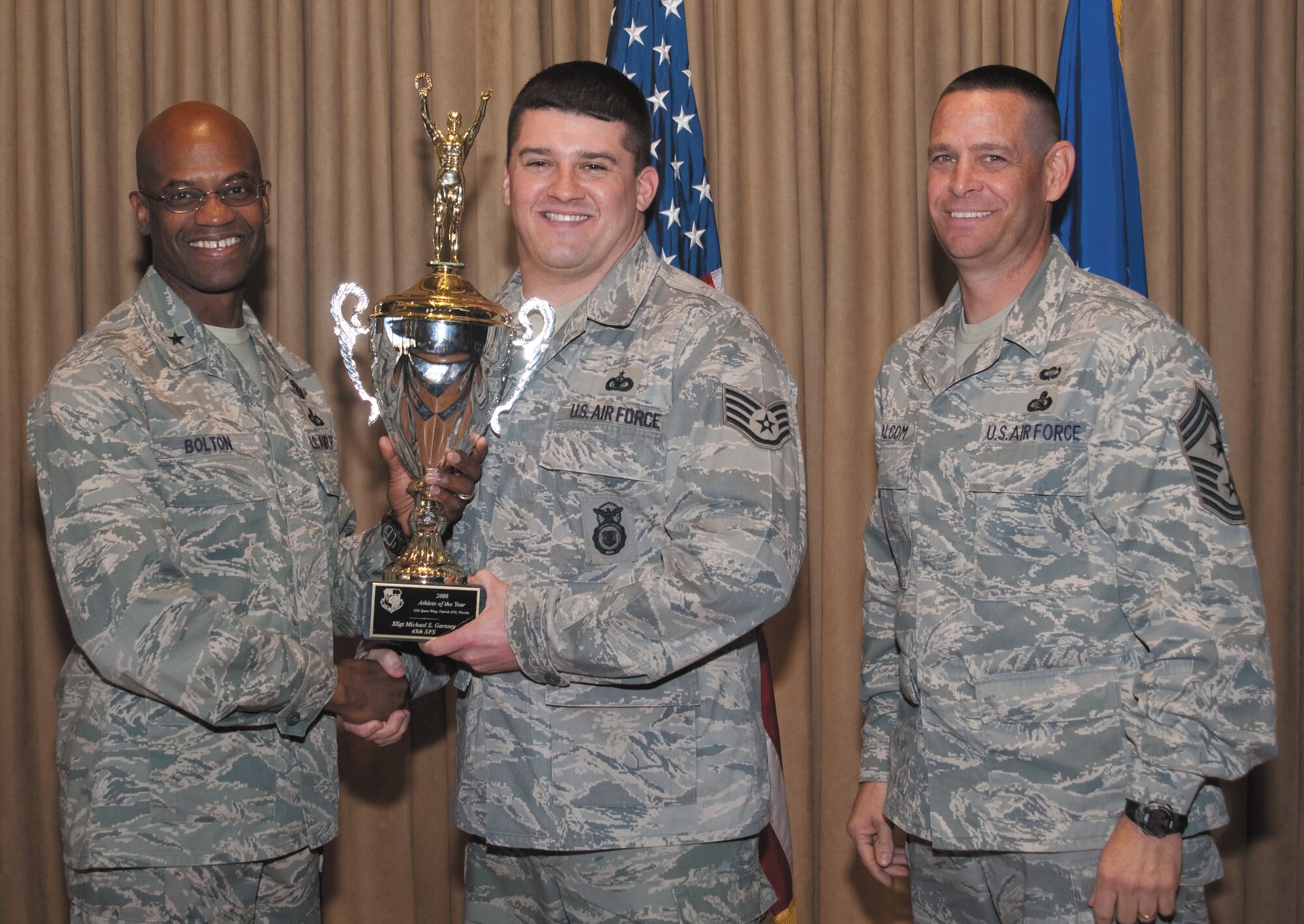 Brig. Gen. Edward L. Bolton, Jr. (left), 45th Space Wing commander, and Command Chief Master Sgt. Larry Malcom (right) present Staff Sgt. Michael Garnsey of the 45th Security Forces Squadron with the Wing's "Athlete of the Year" award during the Sports Banquet at The Tides Jan. 9. (U.S. Air Force photo by Jim Laviska)