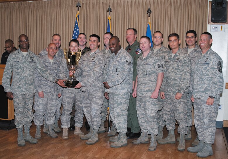 Brig. Gen. Edward L. Bolton, Jr. (left), 45th Space Wing commander, and Command Chief Master Sgt. Larry Malcom (right) are all smiles as they present the Commander's Cup for athletic acheivement to the members of the Launch Support Squadron during the Sports Banquet at The Tides Jan. 9. (U.S. Air Force photo by Jim Laviska)