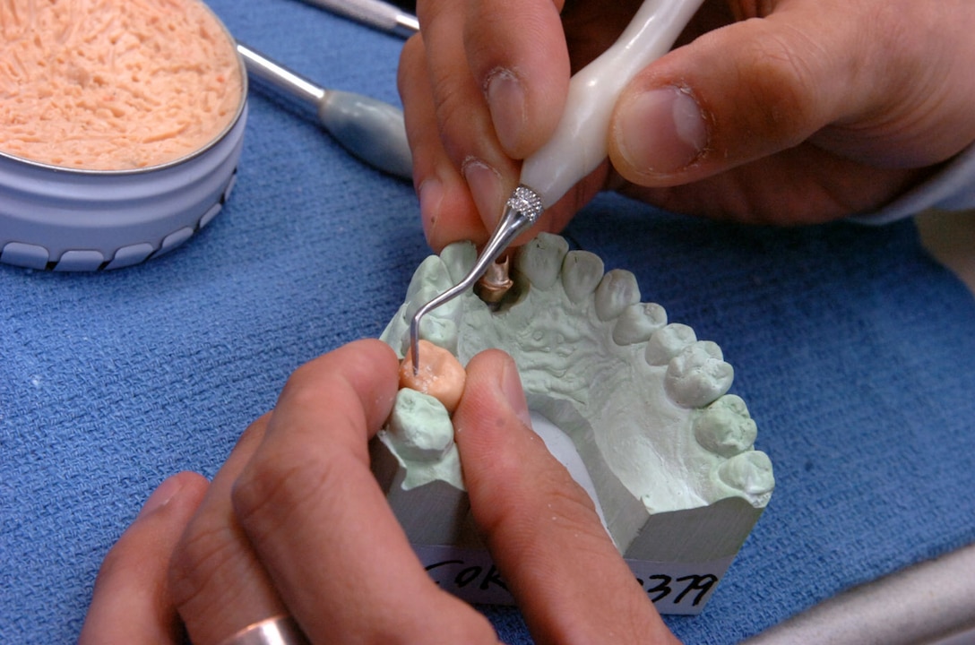 A dental laboratory technician sculpts a wax tooth anatomy mold prior to it becoming an all ceramic dental crown. (U.S. Air Force photo by Bobby Jones)
