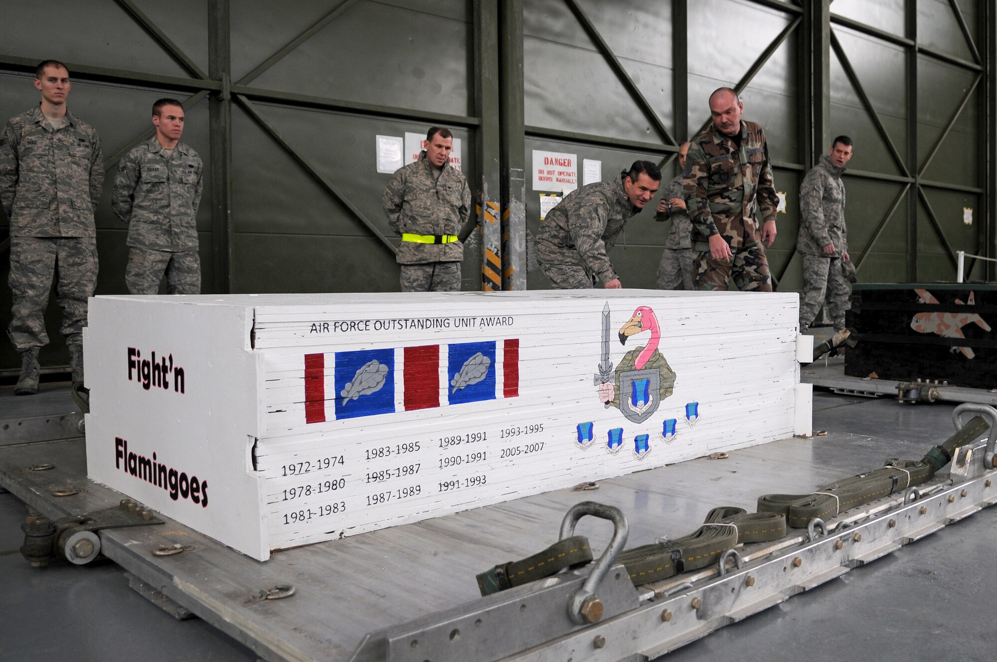 Master Sgt. David Hudson (right), 435th Logistics Readiness Squadron Aerial Delivery Riggers, presents a 435th Air Base Wing painted heavy-cargo box to Col. Donald Bacon, 435 ABW commander at Ramstein Air Base Jan. 16, 2009. Airmen in the 435th LRS painted each of the heavy-cargo boxes with different tributes to military and U.S. events such as September 11 and Pearl Harbor. Their latest tribute was to Colonel Bacon and the 435th ABW. (U.S. Air Force photo by Airman 1st Class Grovert Fuentes-Contreras)