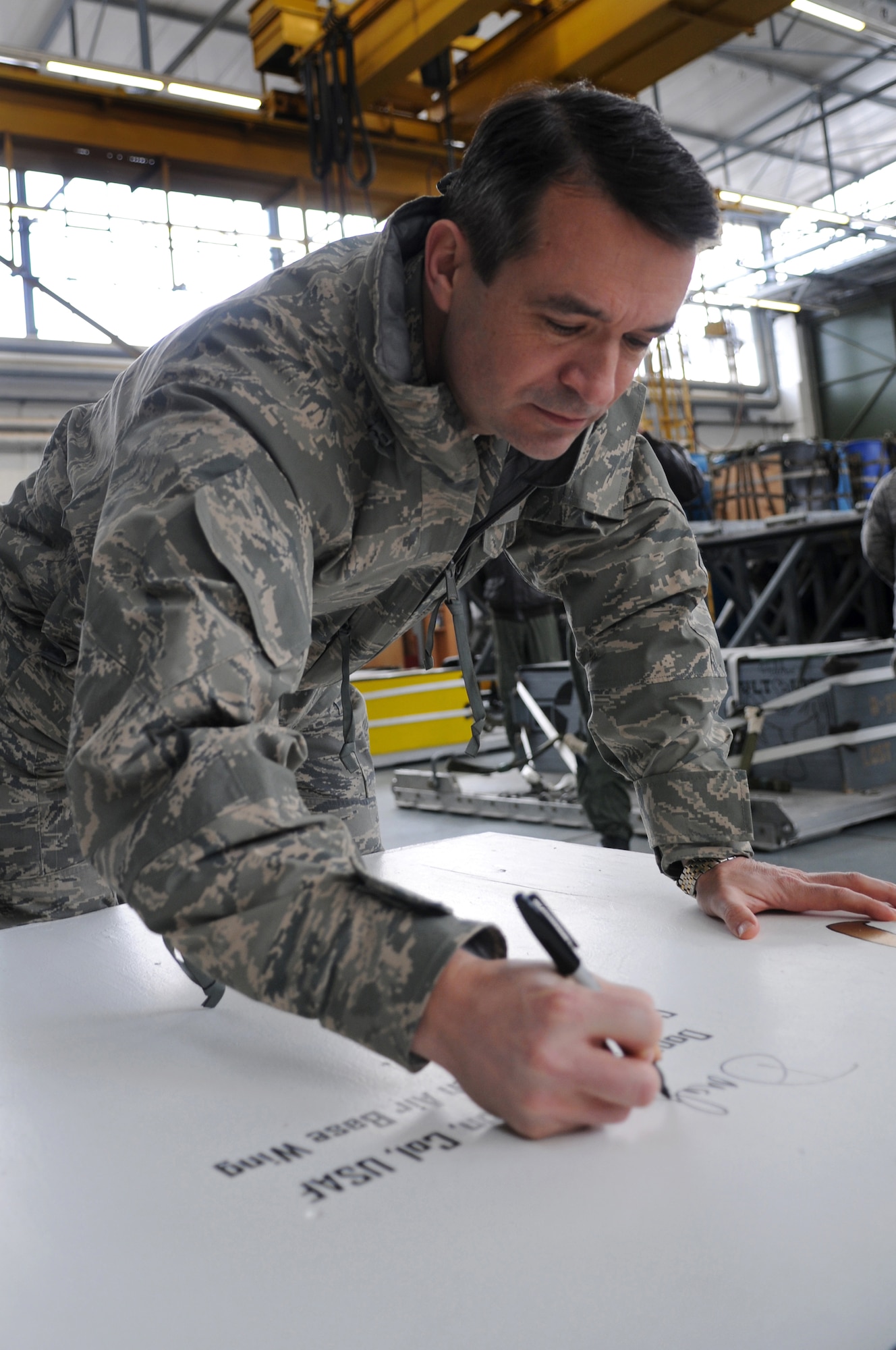 Col. Donald Bacon, 435th Air Base Wing commander, signs the 435th ABW painted heavy-cargo box presented to him at Ramstein Air Base Jan. 16, 2009. Airmen in the 435th Logistics Readiness Squadron painted each of the heavy-cargo boxes with different tributes to military and U.S. events such as September 11 and Pearl Harbor. Their latest tribute was to Colonel Bacon and the 435th ABW. (U.S. Air Force photo by Airman 1st Class Grovert Fuentes-Contreras)