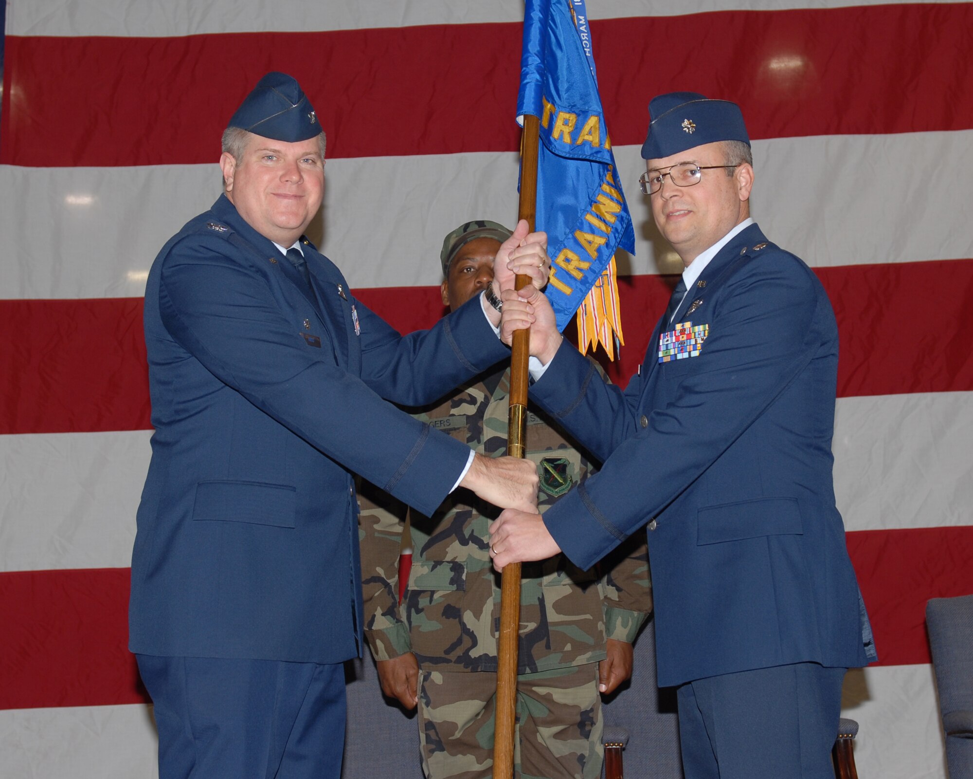 Colonel Terry Ross, 340th Flying Training Group, Air Force Reserve Command, Randolph AFB, Texas, hands the 43rd Flying Training Squadron guidon to Lt. Col. Brian Bowman in a change of command ceremony Jan. 9 in the BLAZE Hangar. Colonel Bowen was previously the director of operations here prior to assuming command of the 43rd FTS. (U.S. Air Force photo by Melissa Duncan)