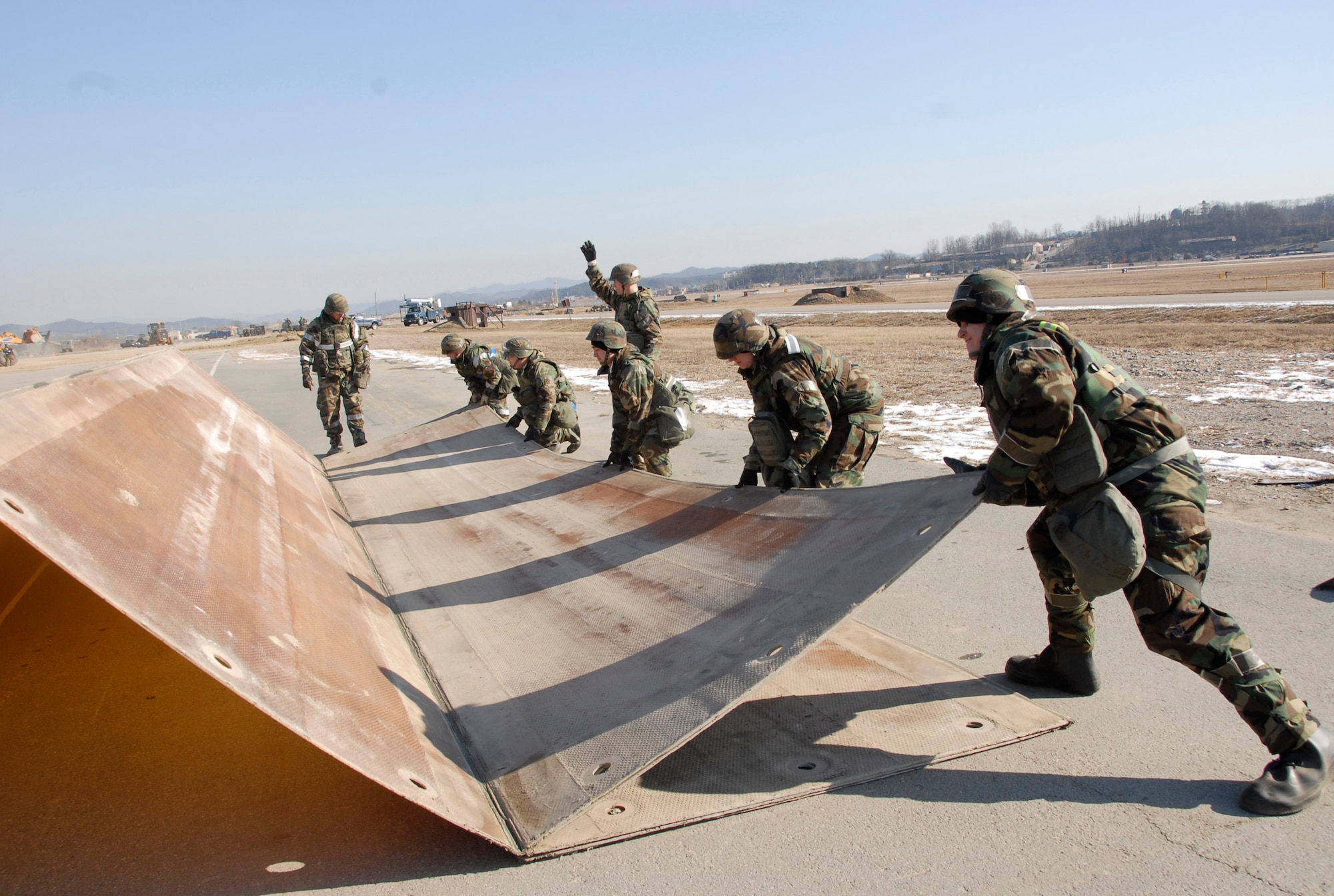 Airmen from the 51st Civil Engineer Squadron Airfield Damage Repair team place a folding fiberglass mat over a simulated crater to cover loose debris during Exercise Beverly Bulldog 09-01 on Osan Air Base Jan. 15.  The 51st Fighter Wing is currently undergoing a week-long Operational Readiness Exercise to test its ability to conduct war-time missions. (US Air Force photo by Staff Sgt. Scottie T. McCord)