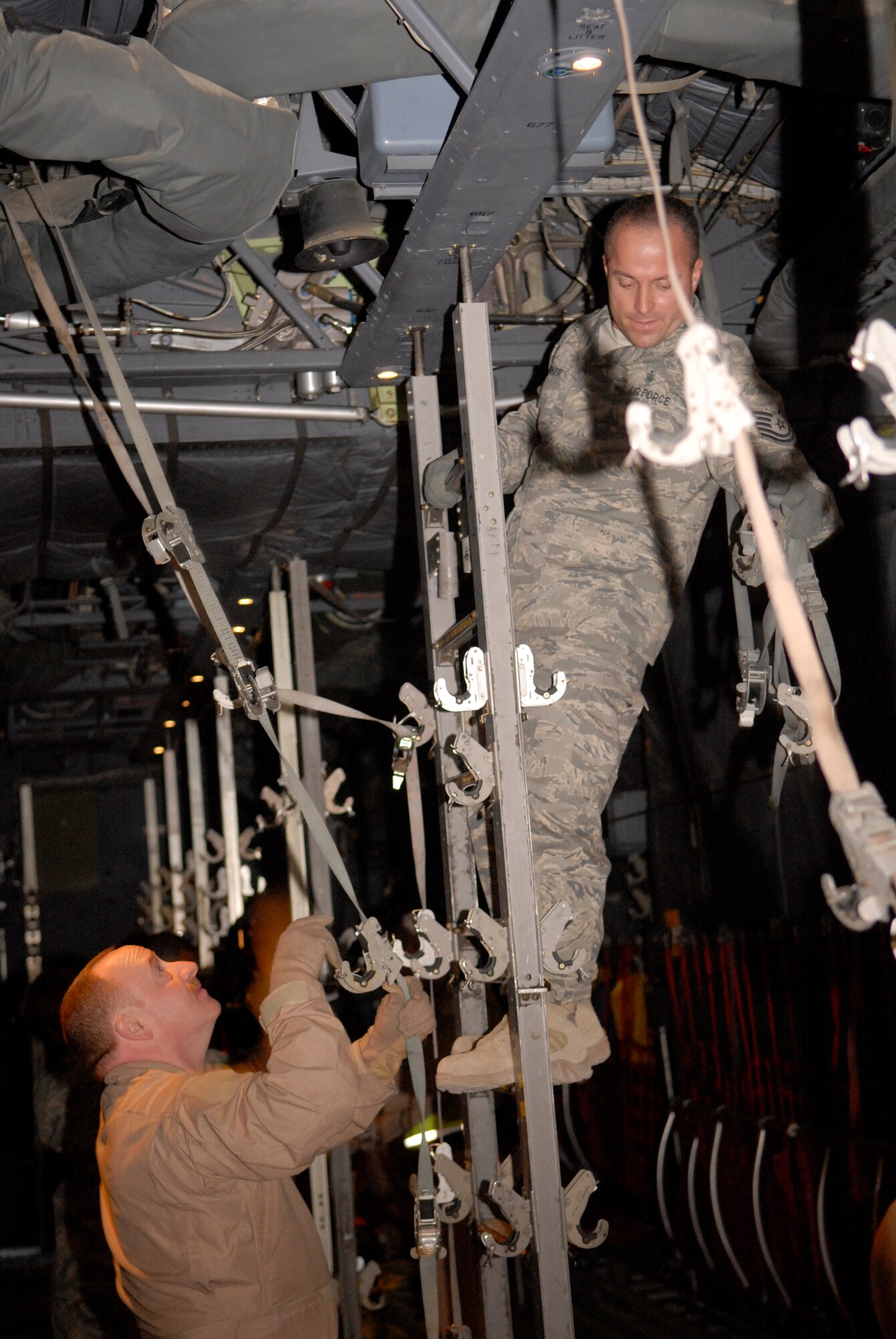 Tech. Sgt. Keith Barker, 379th Expeditionary Aeromedical Evacuation Squadron ground crew NCOIC, and Master Sgt. Michael Granlund, 379 EAES aircrew, secure hooks to hold litters on a C-130 for transporting patients on board, Jan. 11, 2009, at an undisclosed location in Southwest Asia.  The ground crew loads medical supplies onto aircraft to support patients being transported in the area of operations in support of Operation Iraqi and Enduring Freedom, and Combined Joint Task Force-Horn of Africa.  (U.S. Air Force photo by Airman 1st Class Andrew Satran/Released)