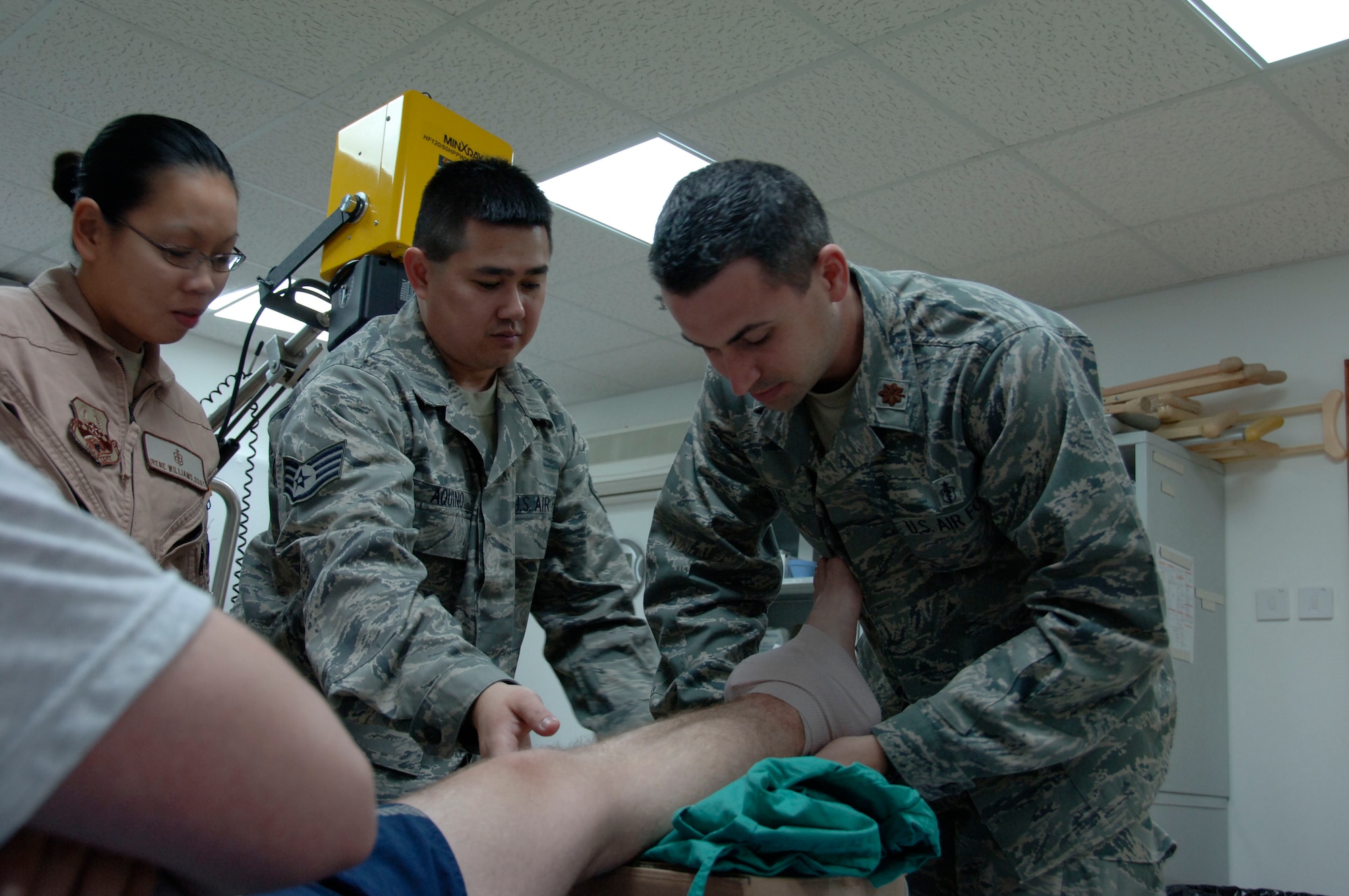 SOUTHWEST ASIA -- Maj. Stephen Titus, 380th Expeditionary Medical Group surgeon general, adjusts a cold compress on a severe ankle sprain with the assistance of Staff Sgt. Edwardson Aquino, an independent duty medical technician, while Staff Sgt. Irene Williams, also an IDMT, looks on. With an increase in mild temperatures, there has been an increase in sports related injuries at the medical clinic. Airmen are encouraged to properly warm up, stretch and wear proper protective gear when engaging in physical activities. (U.S. Air Force photo by Staff Sgt. Mike Andriacco) (Released)