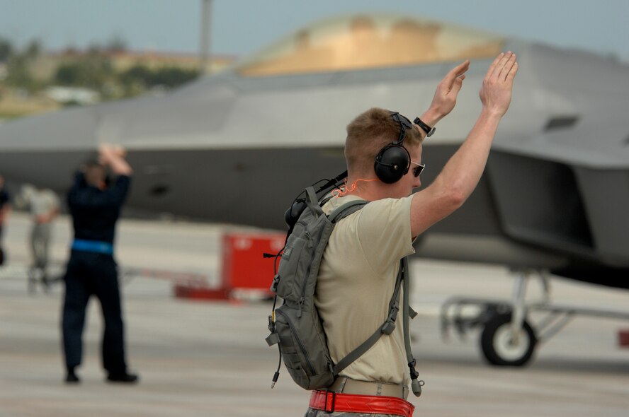 Tech. Sgt. Bryce Kelsey marshals in an F-22 Raptor from Elmendorf Air Force Base, Alaska at Andersen Air Force, Guam on Jan. 18. Andersen received 12 of the $140 million dollar aircraft, and more than 250 Airmen have already arrived at the base to begin a three month deployment as the Pacific's Theater Security Package. The stealth-fighters, along with associated maintenance and support personnel, are deployed as the 90th Expeditionary Fighter Squadron and will participate in various exercises that provide routine training in an environment different from their home station. Sergeant Kelsey is a crew chief from Elmendorf, Alaska.
(U.S. Air Force photo/ Master Sgt. Kevin J. Gruenwald) released




















  












 











































  












 

























