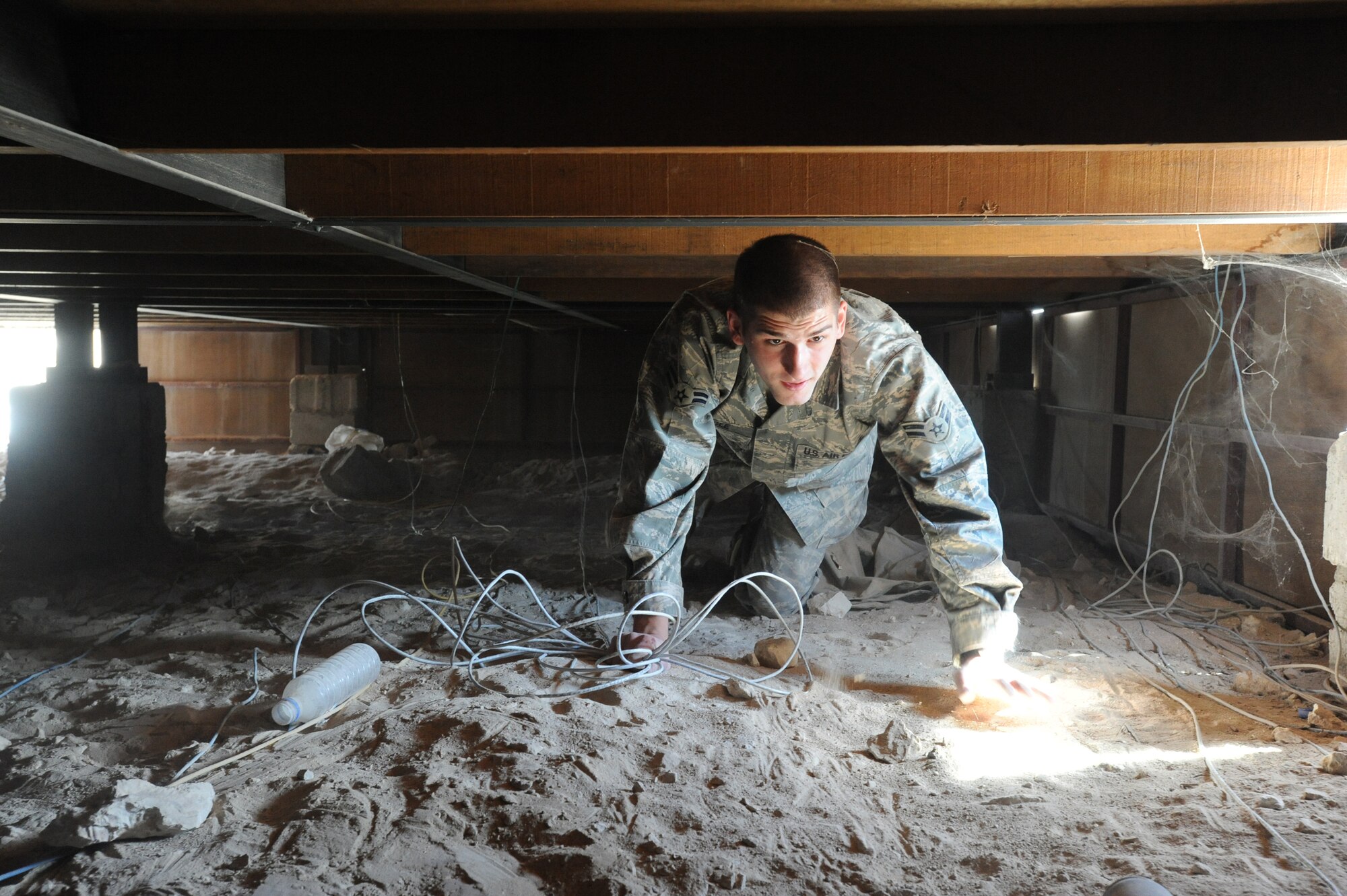 Airman 1st Class Uriah Beagle, a 379th Expeditionary Communication Squadron telephone maintenance technician, pulls catergory 5 (CAT5) wire underneath a compound building, Jan. 18, 2009, in an undisclosed location in Southwest Asia.  CAT5 wire is a standard wire used to connect computers to the Local Area Network.  Airman Beagle is originally from Bloomsburg, Pa. and is deployed from McChord Air Force Base, Wash., in support of Operations Iraqi and Enduring Freedom and Joint Task Force-Horn of Africa (U.S. Air Force Photo by Staff Sgt. Joshua Garcia/Released)