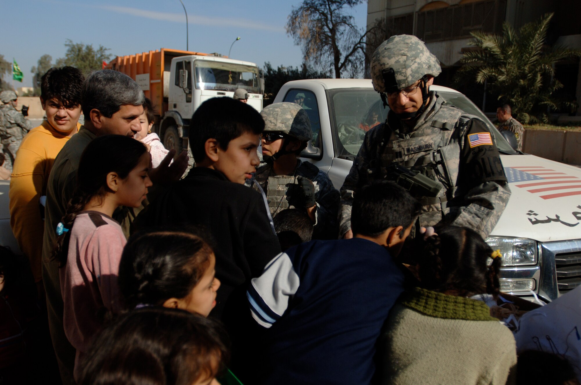 Capt. Ben Washburn, 732nd Expeditionary Security Forces Squadron Detachment 4 operations officer, hands out toys, school supplies and clothes while on foot-patrol in an apartment complex in Baghdad, Iraq, International Zone Jan. 10. The items were gathered by a group of volunteer servicemembers at Joint Base Balad, Iraq, called the Kids of Iraq. The items come from donators in the United States. Washburn currently deployed from Vogelway, Germany is a native of Colorado Springs, Colo. (U.S. Air Force photo/Tech. Sgt. Craig Lifton)
