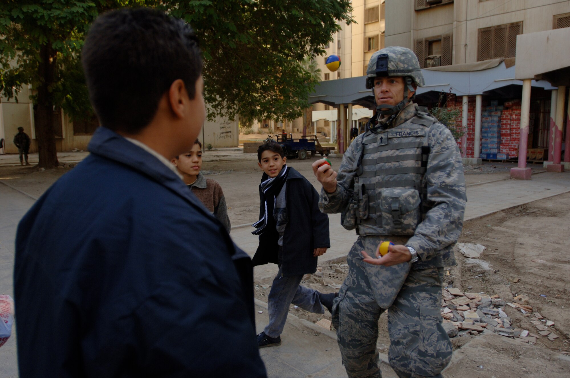 Chaplain (Capt.) Kelvin Francis, 732nd Air Expeditionary Group Religious Support Team, currently deployed from Shaw Air Force Base, S.C., while on foot-patrol in a apartment complex in Baghdad, Iraq, International Zone on Jan. 10, entertains Iraqi children by juggling balls. Francis is a native of Jacksonville, Fla. (U.S. Air Force photo/Tech. Sgt. Craig Lifton)