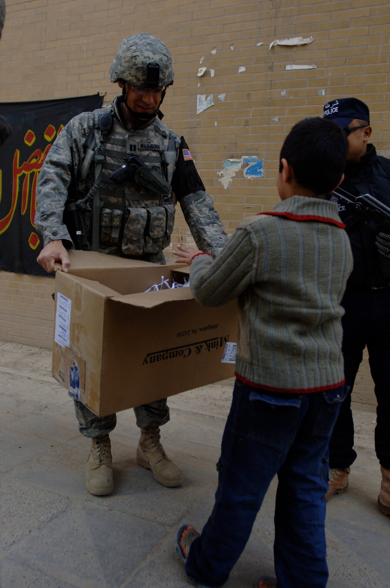 Capt. Ben Washburn, 732nd Expeditionary Security Forces Squadron Detachment 4 operations officer, hands out toys, school supplies and clothes while on foot-patrol in an apartment complex in Baghdad, Iraq, International Zone Jan. 10. The items were gathered by a group of volunteer servicemembers at Joint Base Balad, Iraq, called the Kids of Iraq. The items come from donators in the United States. Washburn, currently deployed from Vogelway, Germany is a native of Colorado Springs, Colo. (U.S. Air Force photo/Tech. Sgt. Craig Lifton)