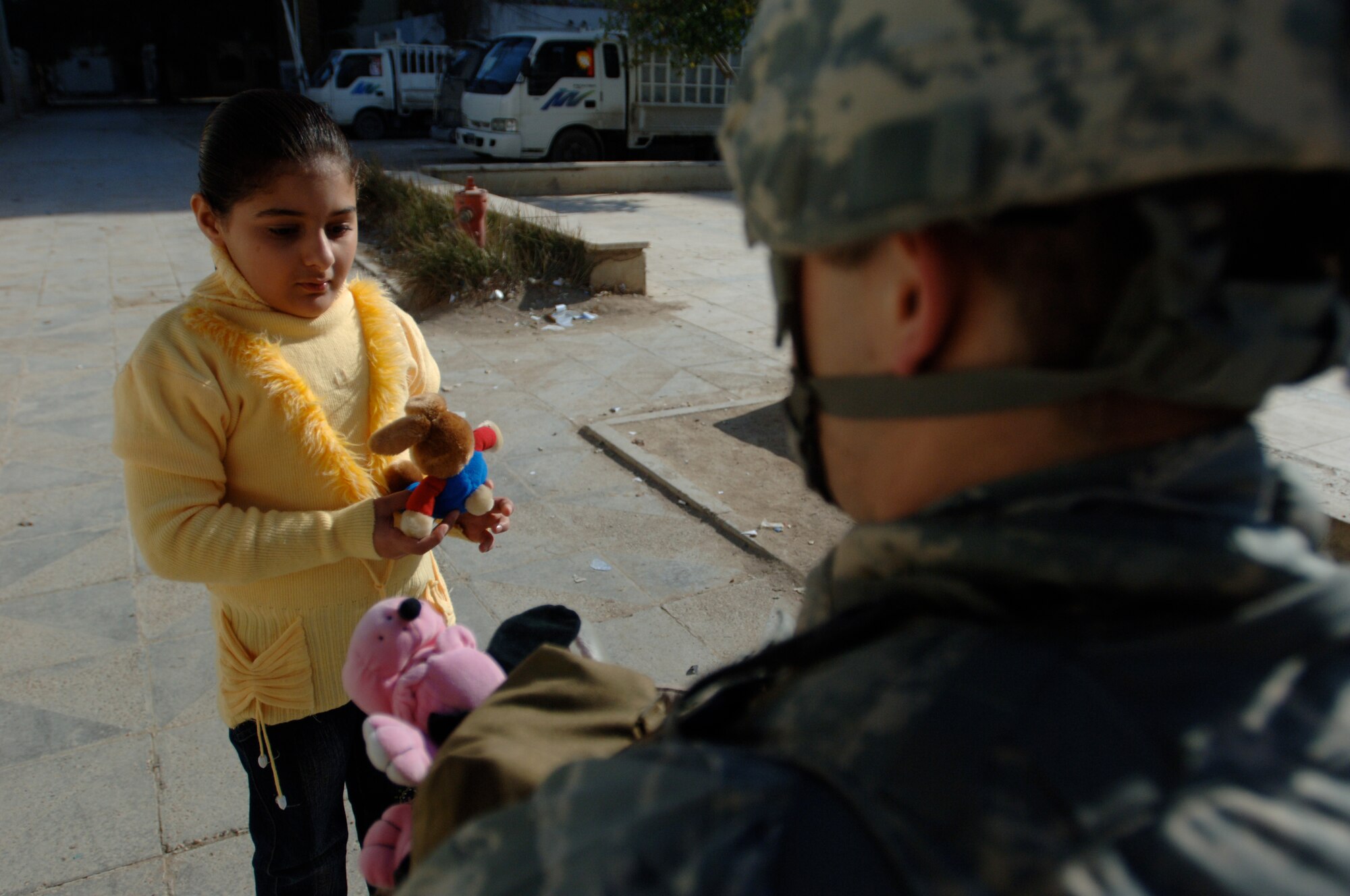 A young Iraqi girl in an apartment complex inside the Baghdad, Iraq, International Zone, accepts toys from a security forces member of the 732nd Expeditionary Security Forces Squadron Detachment 4 Jan. 10. The items were gathered by a group of volunteer servicemembers at Joint Base Balad, Iraq, called the Kids of Iraq. The items come from donators in the United States. (U.S. Air Force photo/Tech. Sgt. Craig Lifton)
