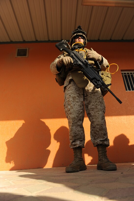 Cpl. Tra C. Neal, fire team leader, Combat Logistics Battalion, 26th MEU from Choctaw, Okla., is armed with a squad automatic weapon, keeping a vigilant eye on the mock embassy evacuees as they file in front of him for screening. This was during a full evacuation drill, where the participants were loaded onto a Landing Craft, Air Cushion and taken out to USS Carter Hall sailing a few miles off shore.