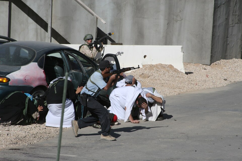 An Iraqi policeman role player protects civilians from mock insurgent attacks Jan. 20, at Medina Wasl, an urban training site at the Army's National Training Center, Fort Irwin, Calif. The role players provide an accurate social environment for units who are gearing up to deploy to Iraq or Afghanistan.