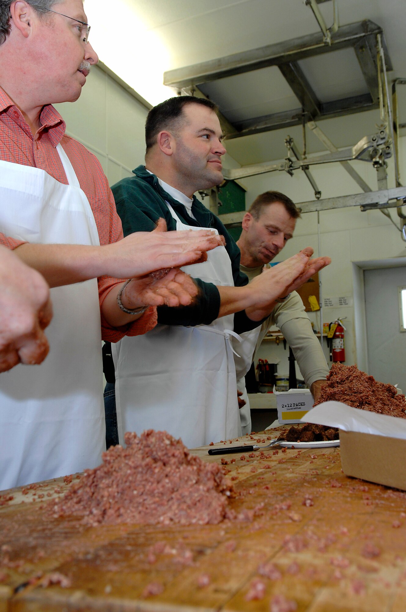 MINOT, N.D. -- Col. Christopher Ayres (center), 91st Missile Wing commander, prepares meatballs at Blom’s Meat Market here Jan. 16, for the upcoming 44th Annual Sportsmen Feed. The feed, which is an annual event designed to build fellowship between the base and local community, was held at the Jimmy Doolittle Center Jan. 18 at Minot AFB. (U.S. Air Force photo by Airman 1st Class Benjamin Stratton)