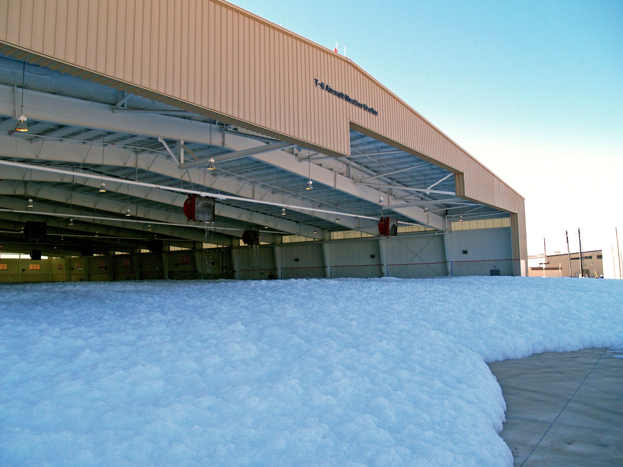 LAUGHLIN AIR FORCE BASE, Texas – High-expansion foam begins to settle after pouring from generators mounted to the ceiling of the newly expanded T-6 weather shelter here Jan. 14.  This was done to test the fire suppression system in the shelter after three new generators had been installed as part of the expansion. (U.S. Air Force photo by 2nd Lt. Eric Jones) 