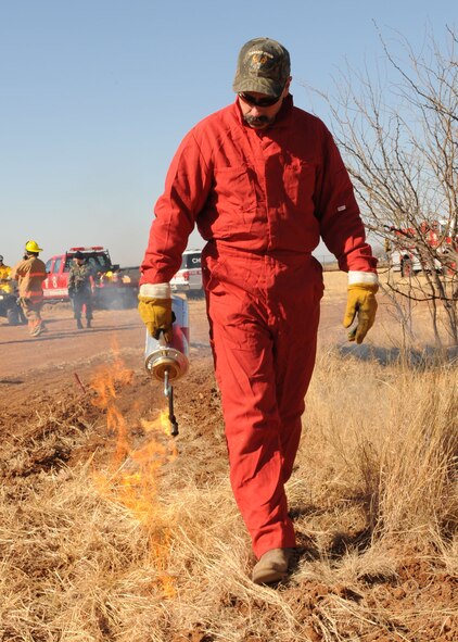 DYESS AIR FORCE BASE, Texas -- Steve Verette, a firefighter from the 7th Civil Engineering Squadron, uses a drip torch to start creating the "black line" here, Jan. 15. The "black line" prevents the fire from spreading outside the control area.(U.S. Air Force photo by Senior Airman Felicia Juenke)