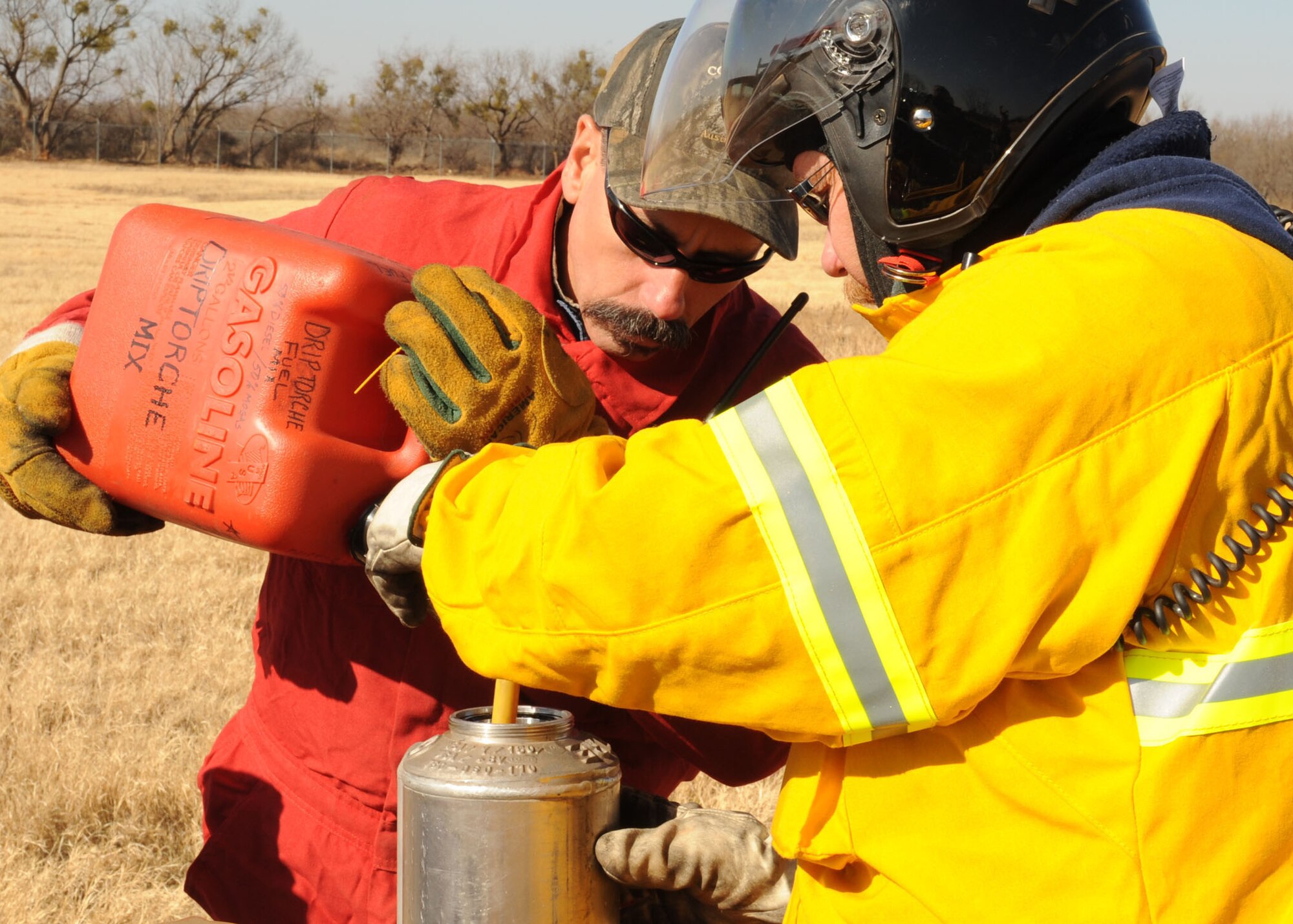 DYESS AIR FORCE BASE, Texas -- Steve Verette and Reed Tate, both firefighters from the 7th Civil Engineering Squadron, prepare a mixture of gasoline and diesel fuel for the drip torches used during a controlled burn here, Jan. 15. Controlled burns are performed in order to help prevent wild fires throughout base.(U.S. Air Force photo by Senior Airman Felicia Juenke)