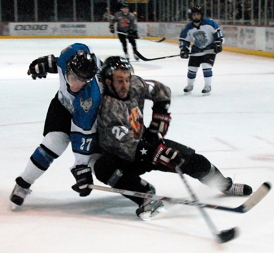 Wichita Falls Wildcats forward Brett Hartung, right, battles Billy Miller, a defenseman for the Wenatchee Wild, for the puck Jan. 17 during the Wildcats annual Military Appreciation Night. The Wildcats wore camouflaged jerseys in honor of the men and women in the nation's armed forces. The Wildcats won 4-3. (U.S. Air Force photo/Mike Litteken)