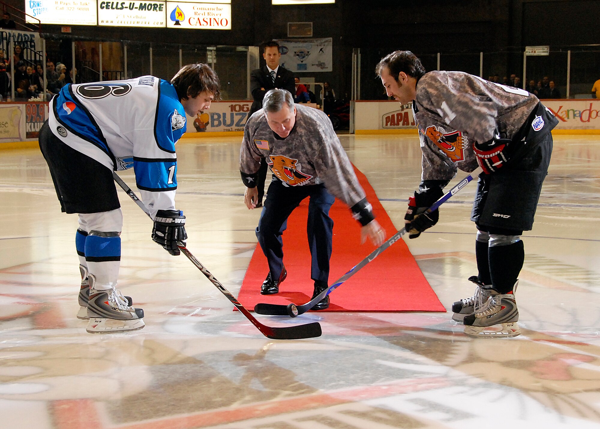 Brig. Gen. O.G. Mannon (center), 82nd Training Wing commander, drops the puck Jan. 17 prior to a game between the Wichita Falls Wildcats and Wenatchee Wild from Wenatchee, Wash, to start the annual Military Appreciation Night. Wildcat Brett Hartung, right, and the Wild's Michael Voran joined the general on the ice for the ceremonial drop. The Wildcats won 4-3. (U.S. Air Force photo/Mike Litteken)