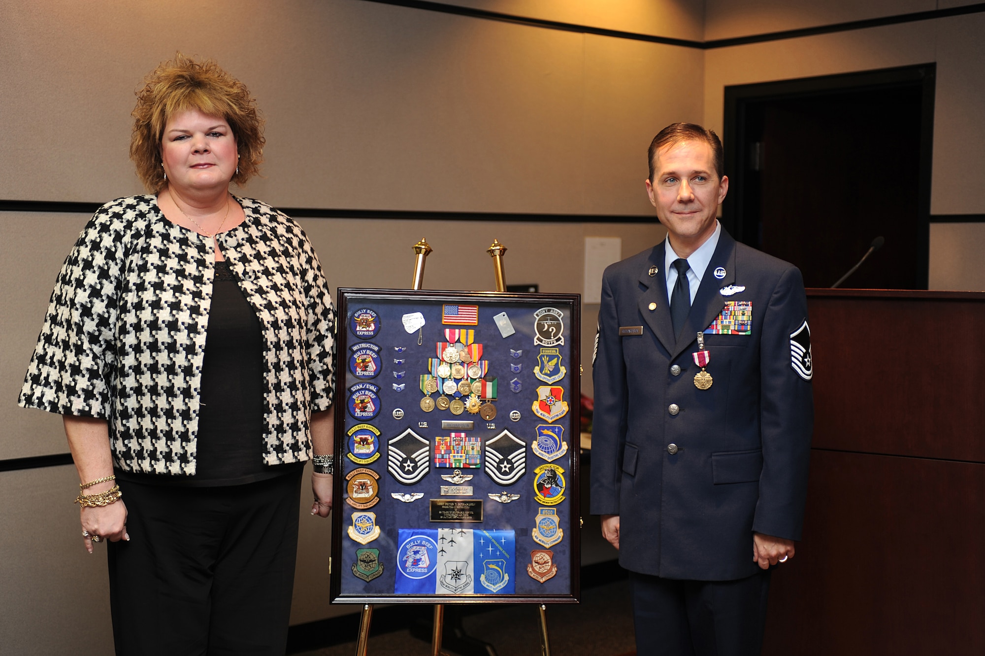 Master Sgt. Peter Richardson and his wife, Dorothy, pose for a picture next to his shadow box during his retirement ceremony in the U.S. Air Force Expeditionary Center on Fort Dix, N.J., Jan. 9, 2009.  Sergeant Richardson was a command tactician for the Combat Aircrew Tactics Studies Course.  He was then selected to fulfill the position of course director for the CATS course in his last years at the Expeditionary Center. (U.S. Air Force Photo/Staff Sgt. Nathan Bevier)