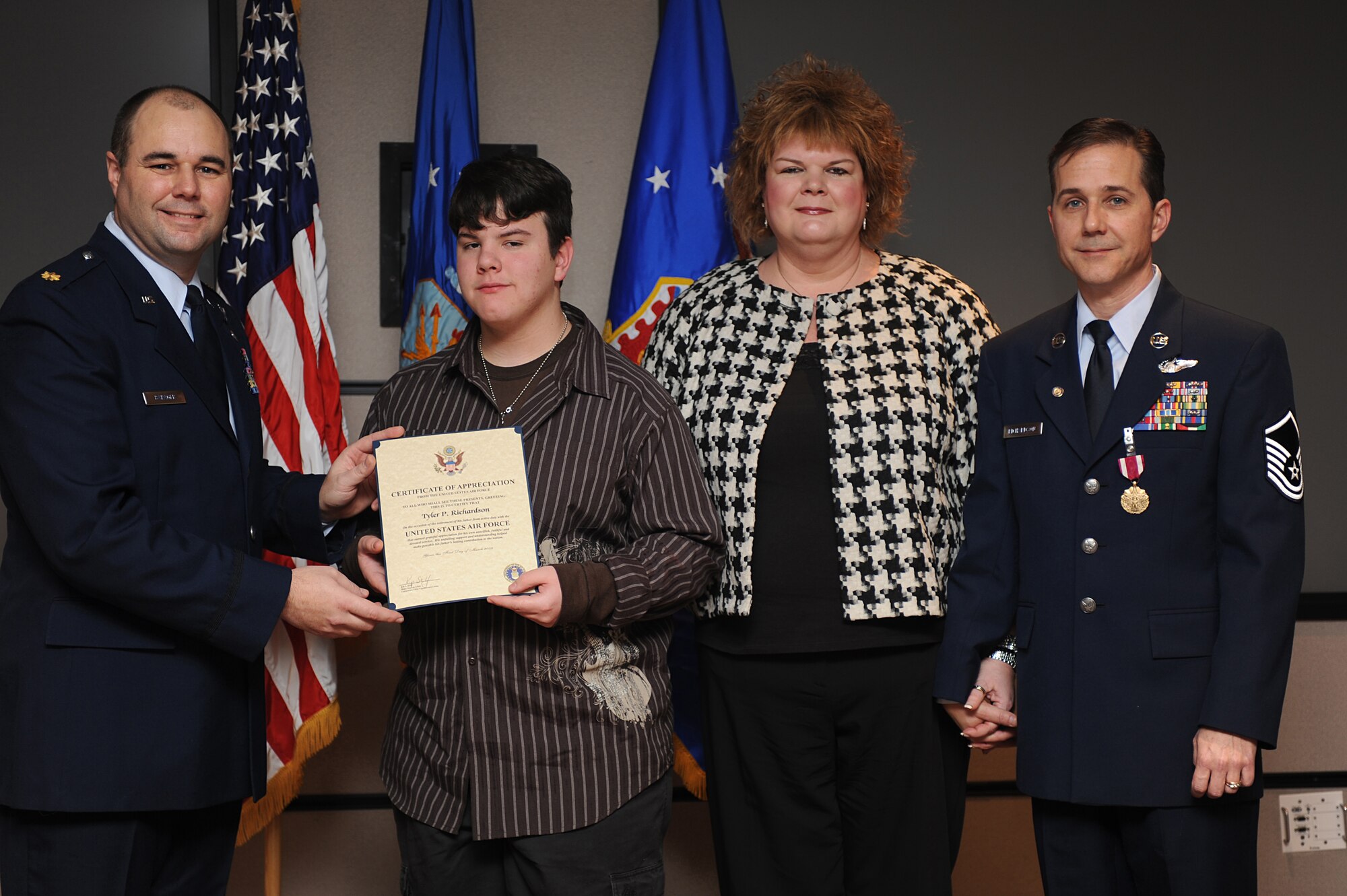 Maj. Robert Barager, Expeditionary Operations School, presents a certificate of appreciation to Tyler, 14-year-old son of Dorothy and Master Sgt. Peter Richardson, during Sergeant Richardson's retirement ceremony in the U.S. Air Force Expeditionary Center on Fort Dix, N.J., Jan. 9, 2009.  Sergeant Richardson was a command tactician for the Combat Aircrew Tactics Studies Course.  He was then selected to fulfill the position of course director for the CATS Course in his last years at the Expeditionary Center. (U.S. Air Force Photo/Staff Sgt. Nathan Bevier)
