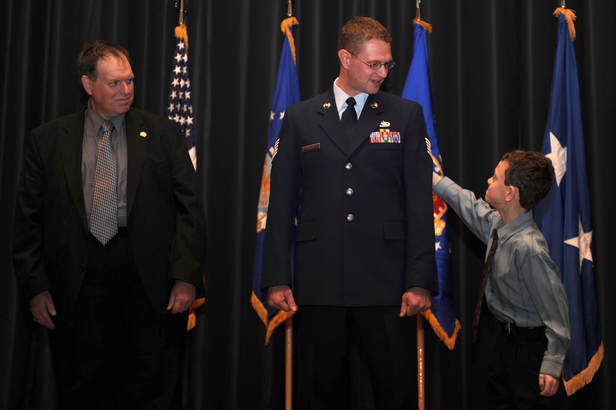 Tech. Sgt. Jonathan McClure, Mobile Command and Control Environmental Control Unit Course director in the U.S. Air Force Expeditionary Center's Mobility Operations School, gets his newly promoted stripes tacked on by his 8-year-old son, Ryan McClure, and father, Gary McClure, during a U.S Air Force Expeditionary Center promotion ceremony at Fort Dix, NJ, Jan. 8, 2009. Sergeant McClure's effective date of promotion was Jan. 1.  (U.S. Air Force Photo/Staff Sgt. Nathan Bevier)
