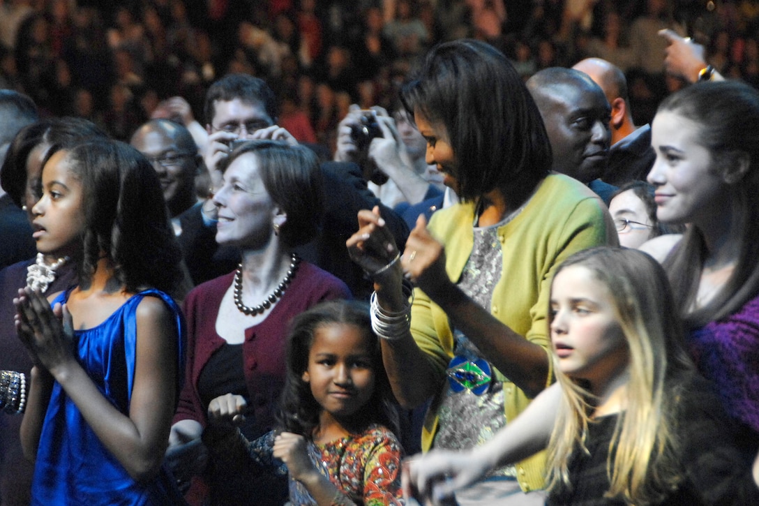 Michelle Obama, wife of President-elect Barack Obama, along with her daughters Malia, left, and Sasha, center, rock out during the “Kids' Inaugural: We Are the Future” concert at the Verizon Center in downtown Washington, D.C., Jan. 19, 2009. Thousands of children from military families around the National Capitol Region gathered to attend the concert. The concert featured performances by Miley Cyrus, the Jonas Brothers, Bow Wow, Demi Lovato and Corbin Blue. Country musician Billy Ray Cyrus appeared on stage and performed with daughter Miley. Keke Palmer and Usher Raymond IV also made appearances, as did comedian and actor George Lopez. Both Mrs. Obama and Jill Biden, wife of Vice President-elect Joe Biden, made speeches during the event. The event was one of many surrounding the Jan. 20 inauguration of President-elect Barack Obama.