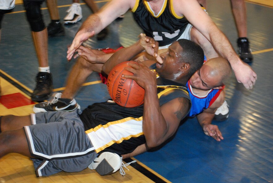 BATTLING IT OUT: Anthony Womble fights to retain possession of the ball in a game against against the Navy team, who ended up winning the 2008 Intramural Basketball Championship Game, Jan. 7, against 452 SFS #1, 57 to 46 after the title game. Navy and 452 SFS #1 went head to head after advancing from two play-off games where  the 7 - 5 Navy team beat the 5 - 7 452 SFS #2 team, 90 to 50, and 4 - 8 452 SFS #1 upset the 12 - 0 452 Comm Squadron team, 53 to 43. (U.S. Air Force photo)