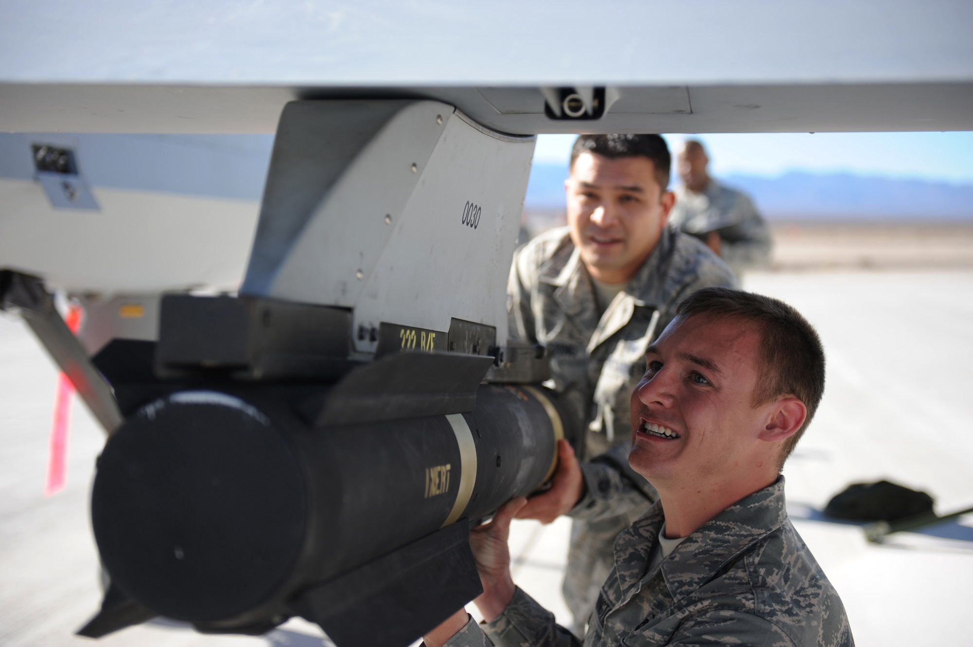 CREECH AFB, Nev. -- Airman 1st Class Aaron Weddington, 432d Maintenance Squadron and Staff Sgt. Delvin Baquering, 432d Aircraft Maintenance Squadron, load a Hellfire missile on a MQ-1B Predator during the 432nd Wing weapons load crew competition held here Jan. 16. (U.S. Air Force photo/Senior Airman Brian Ybarbo)