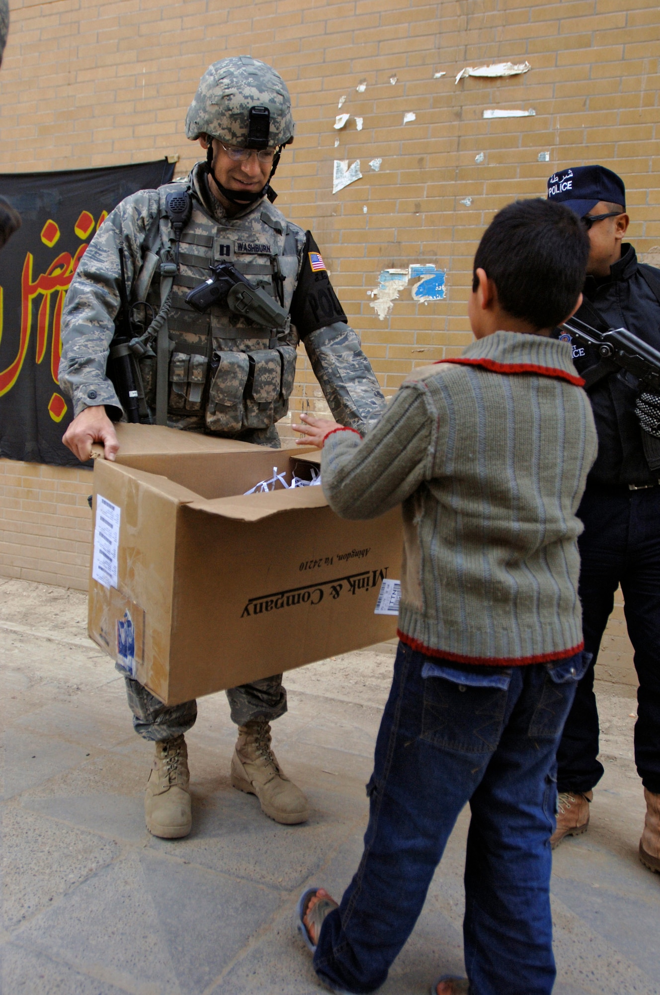 Capt. Ben Washburn hands out toys, school supplies and clothes while on foot-patrol in an apartment complex Jan. 10 in the International Zone of Baghdad, Iraq. The items were gathered by a group of volunteer servicemembers at Joint Base Balad, Iraq, called the Kids of Iraq. The items come from donators in the United States. Captain Washburn is the 732nd Expeditionary Security Forces Squadron Det. 4 operations officer. He is deployed from Vogelway, Germany, and is a native of Colorado Springs, Colo. (U.S. Air Force photo/Tech. Sgt. Craig Lifton) 
