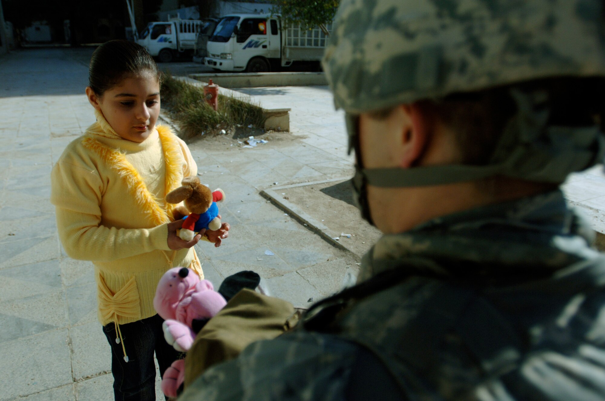 A young Iraqi girl in an apartment complex accepts toys from an Airman of the 732nd Expeditionary Security Forces Squadron Det. 4 Jan. 10 inside the International Zone of Baghdad, Iraq. The items were gathered by a group of volunteer servicemembers at Joint Base Balad, Iraq, called the Kids of Iraq. The items come from donators in the United States. (U.S. Air Force photo/Tech. Sgt. Craig Lifton) 
